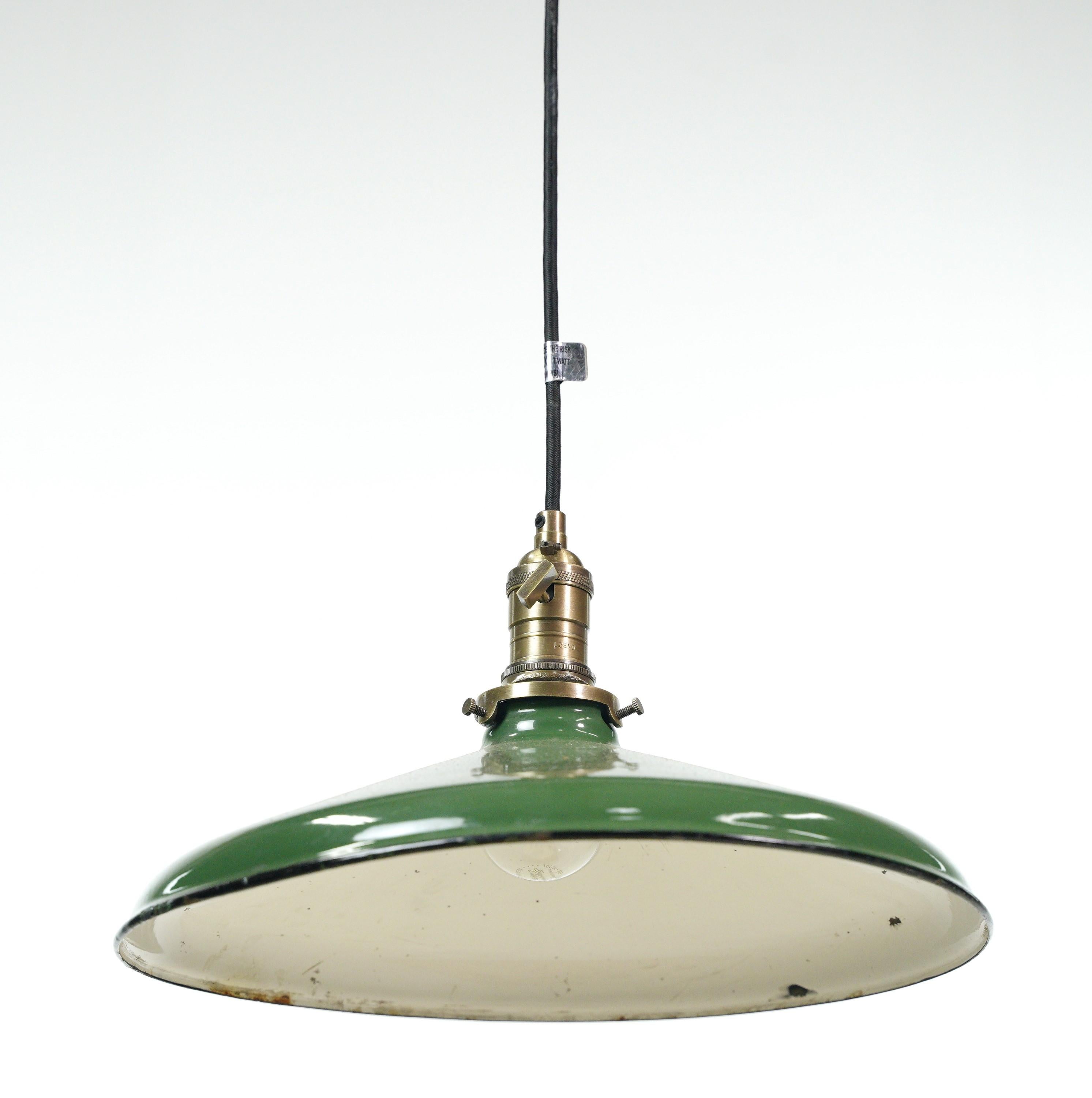 Industrial pendant light featuring a vintage green enameled steel shade with a newly made black cord and antique brass finished fitter. This unique blend of materials and finishes creates a bold statement piece that combines vintage charm with