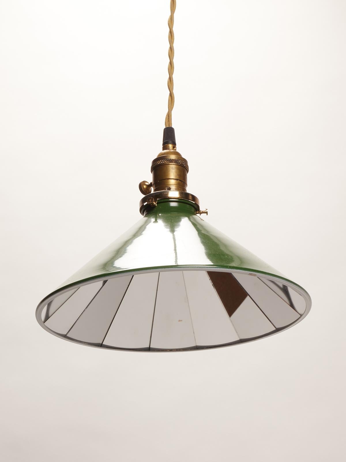 Green enameled metal swinging industrial lamps from a tailoring factory, made out of metal and mirrors, trapezium shape, to reflect the light. USA circa 1920.