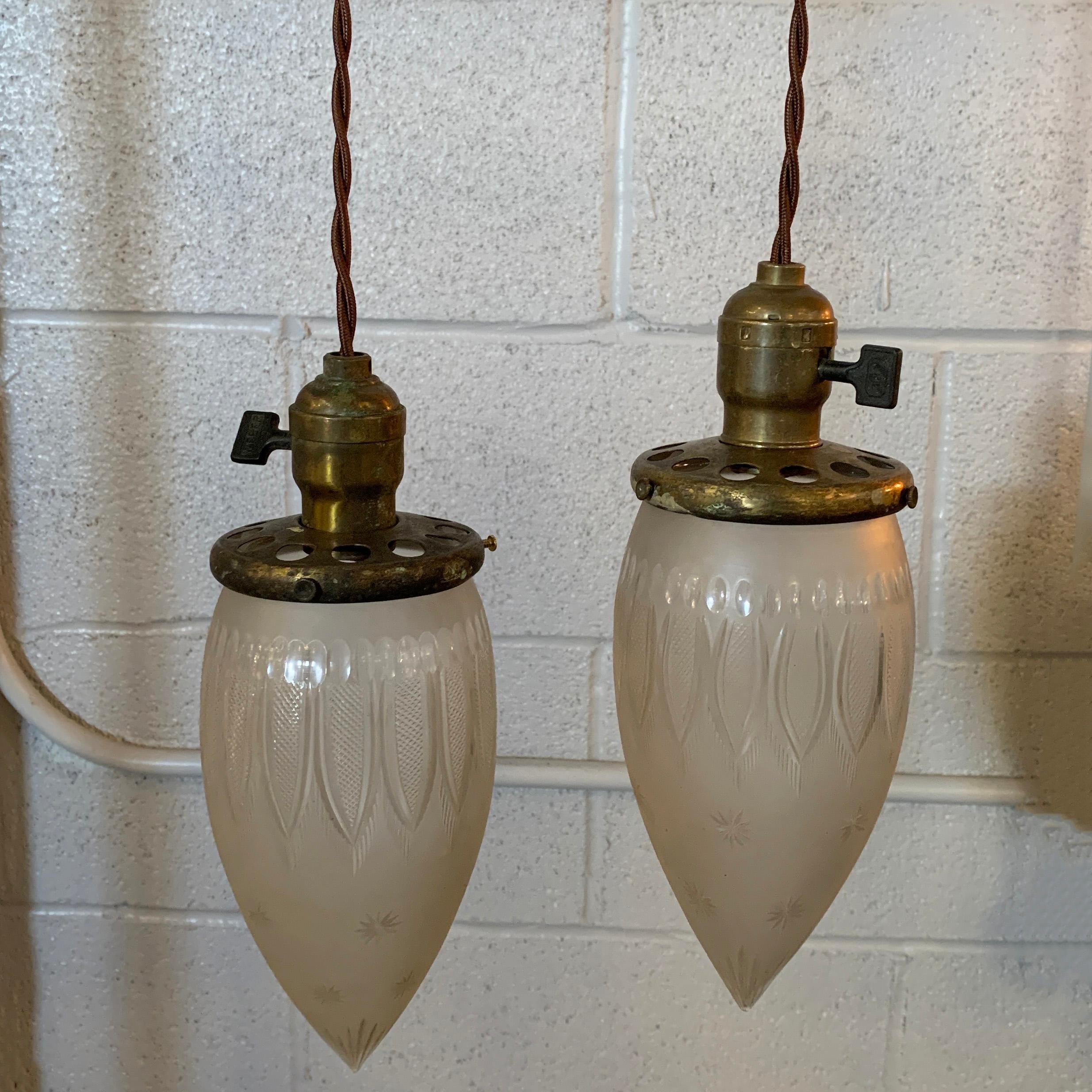 Antique, industrial pendant light features a late 19th century, etched glass, teardrop-shaped shade with brass switch fitter. The pendant is newly wired with 40 inches of braided cloth cord to accept up to a 75 watt bulb. Sold individually, 5