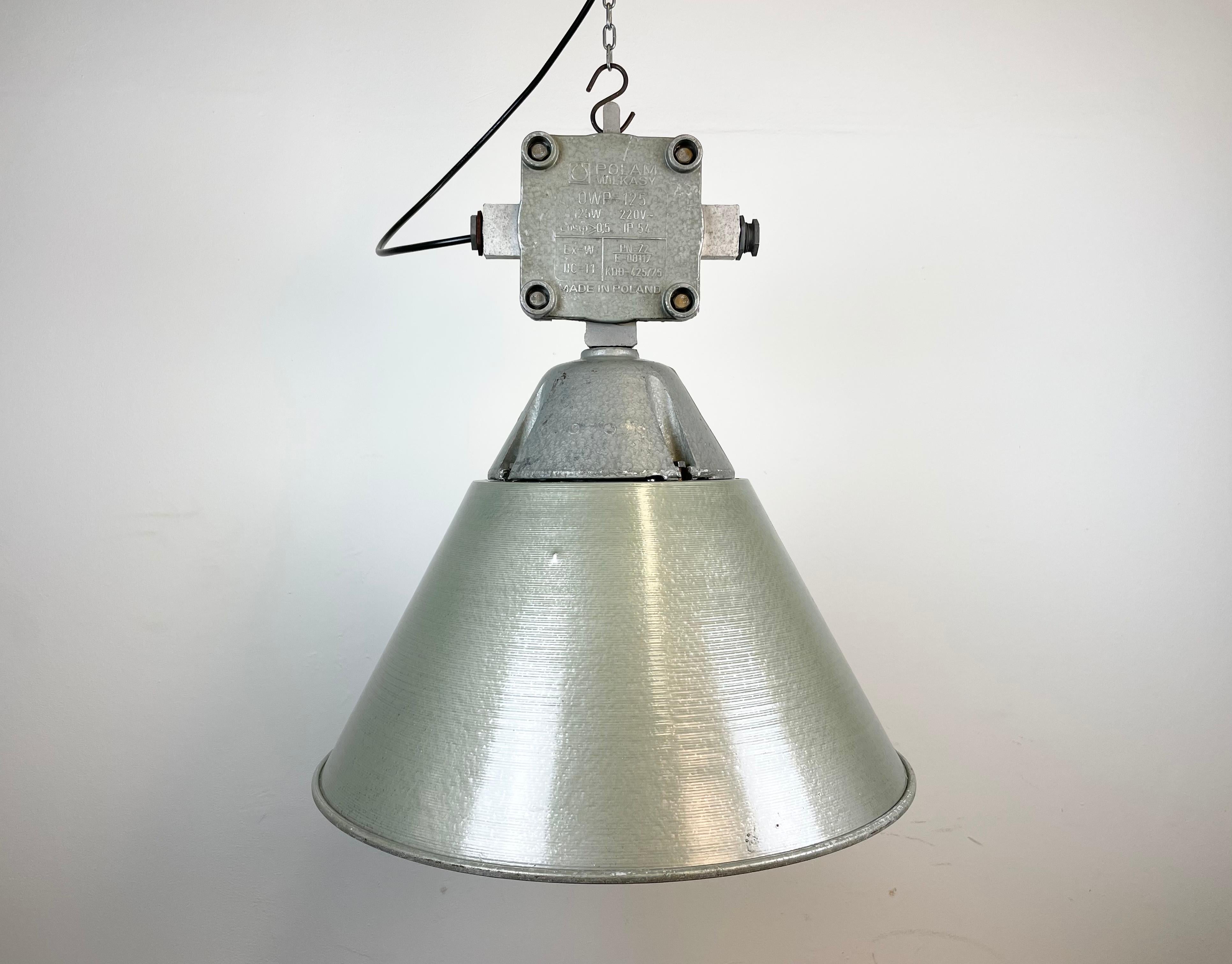 Lampe d'usine industrielle fabriquée par Polam Wilkasy en Pologne dans les années 1970. Il est composé d'un corps en fonte d'aluminium, d'une cage en fer et d'un abat-jour en verre mikl antidéflagrant et en aluminium.
La douille nécessite des