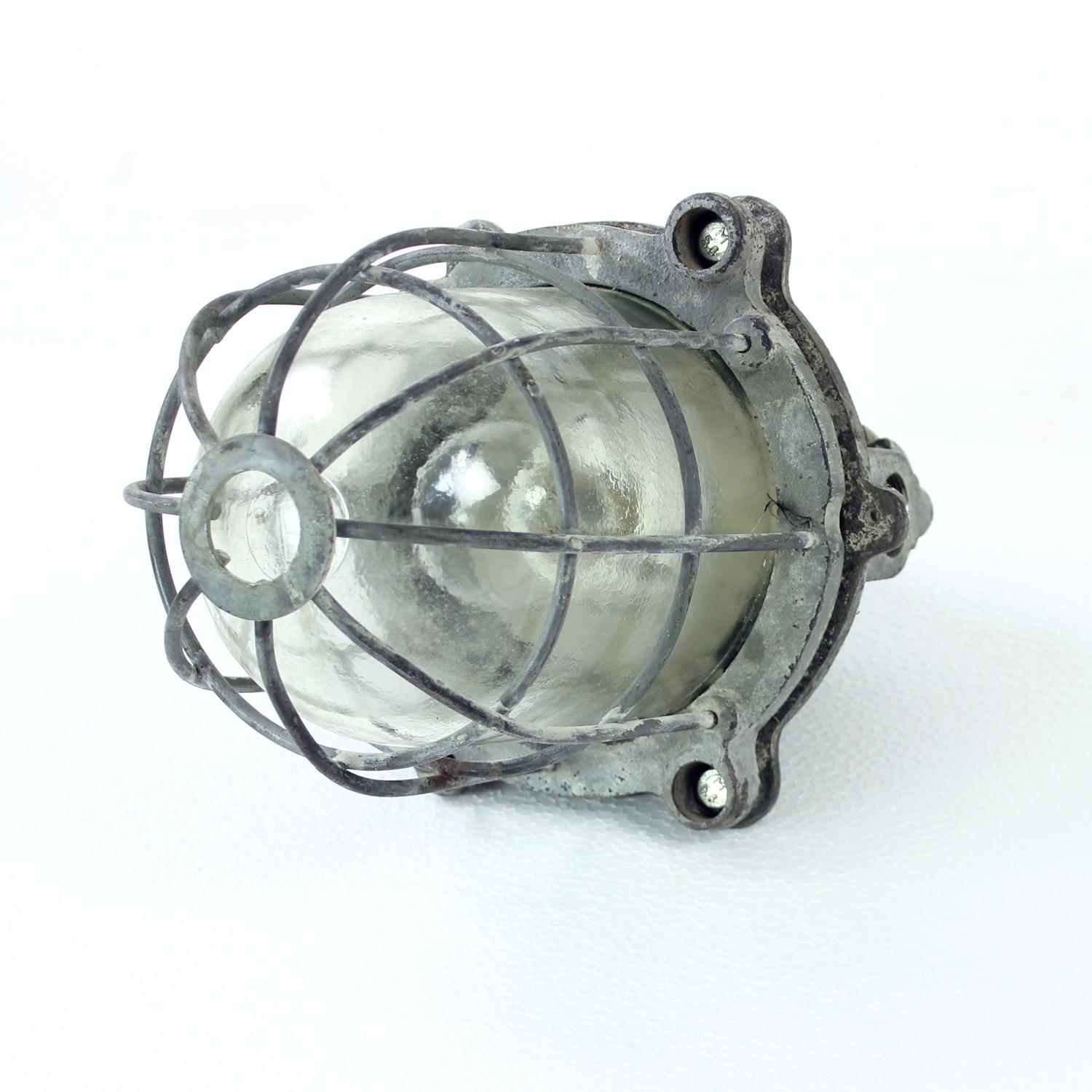Beautiful industrial ceiling light produced in Czechoslovakia in 1940s. The light has been restored by the electrician to be safely used in the homes today. The light has a steel, heavy metal base on which the cage is attached. The glass is a strong