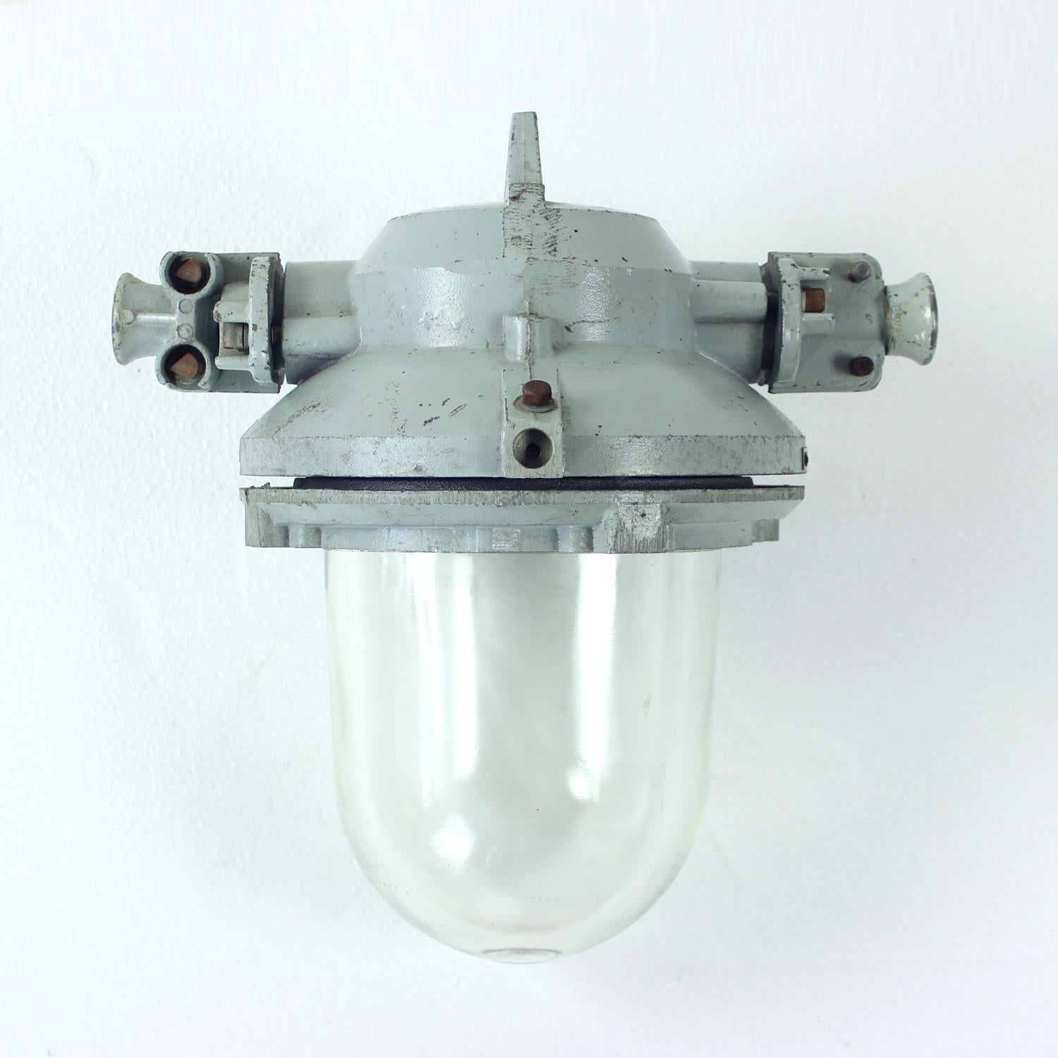 This is a great find, as this light combines the elegance of a light with the industrial charm of the factory light. Original labels still attached. This light has a steel base in grey color and a heavy factory glass shield. The glass is transparent
