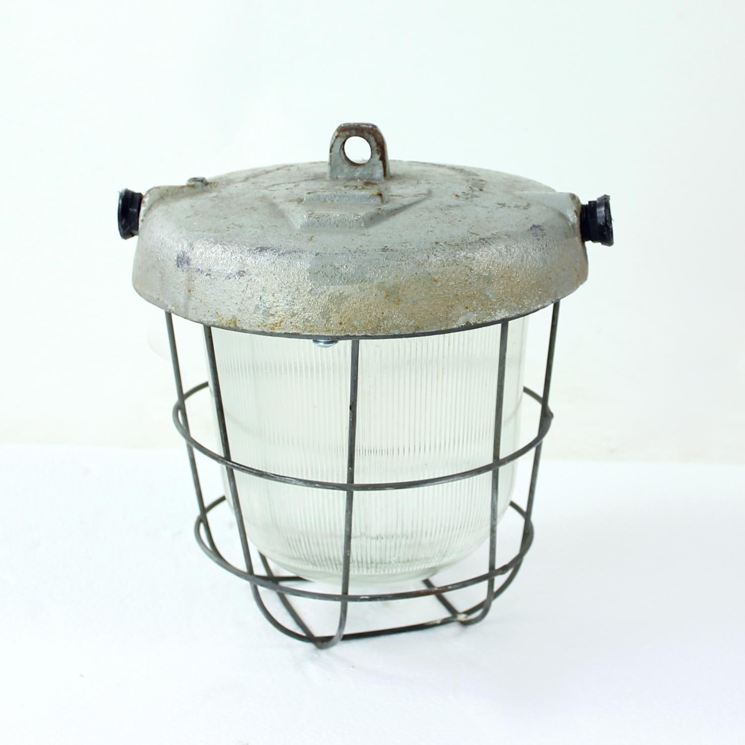 Beautiful factory ceiling light produced in Czechoslovakia in 1950s. The light has a steel base on which a cage and glass shield are connected. The electrical components have been changed and restored to make this great light ready for homes today.