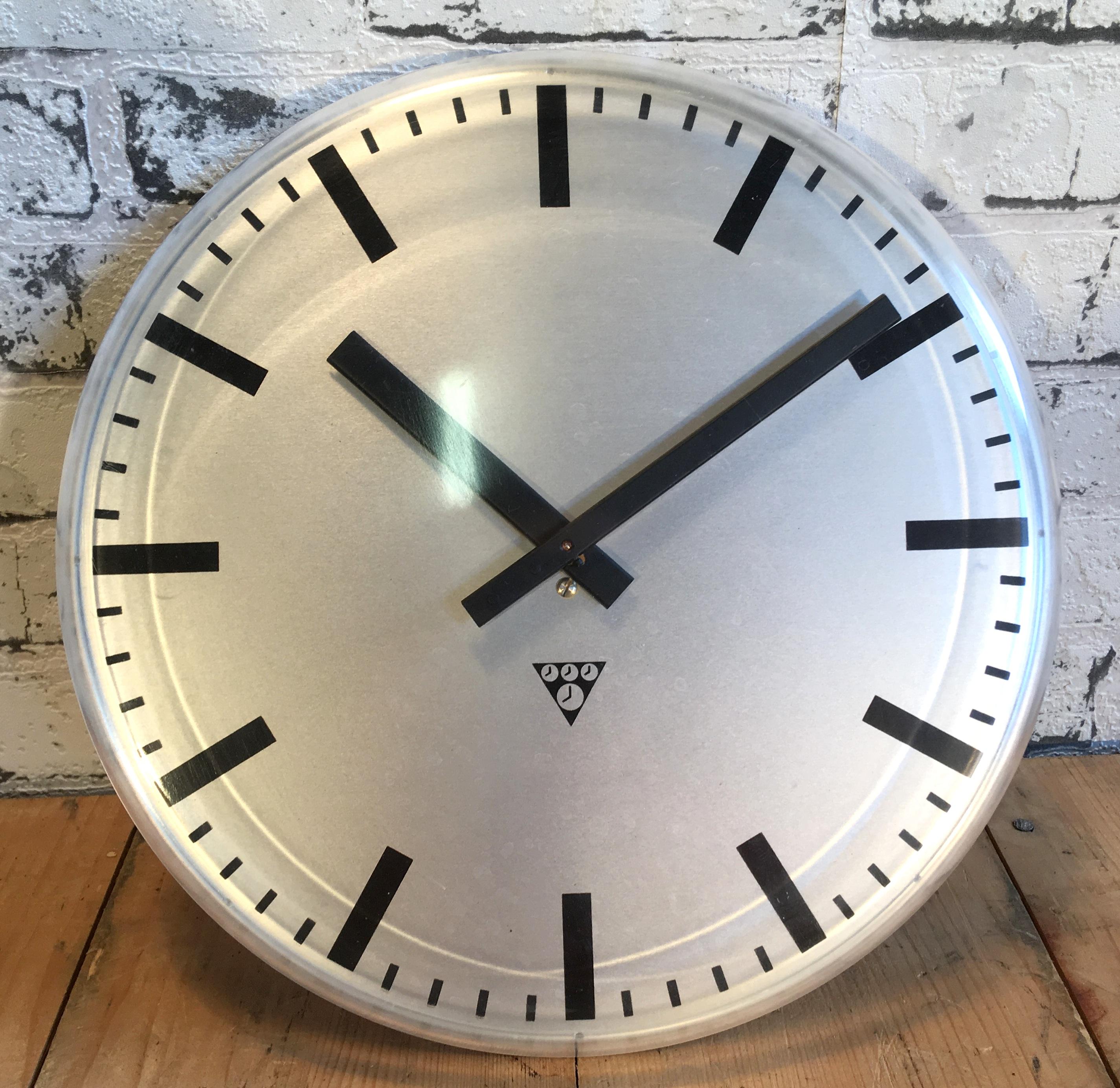 This wall clock was produced by Pragotron in former Czechoslovakia during the 1980s. It features a grey aluminium dial and a curved plastic clear glass cover. The piece has been converted into a battery-powered clockwork and requires only one