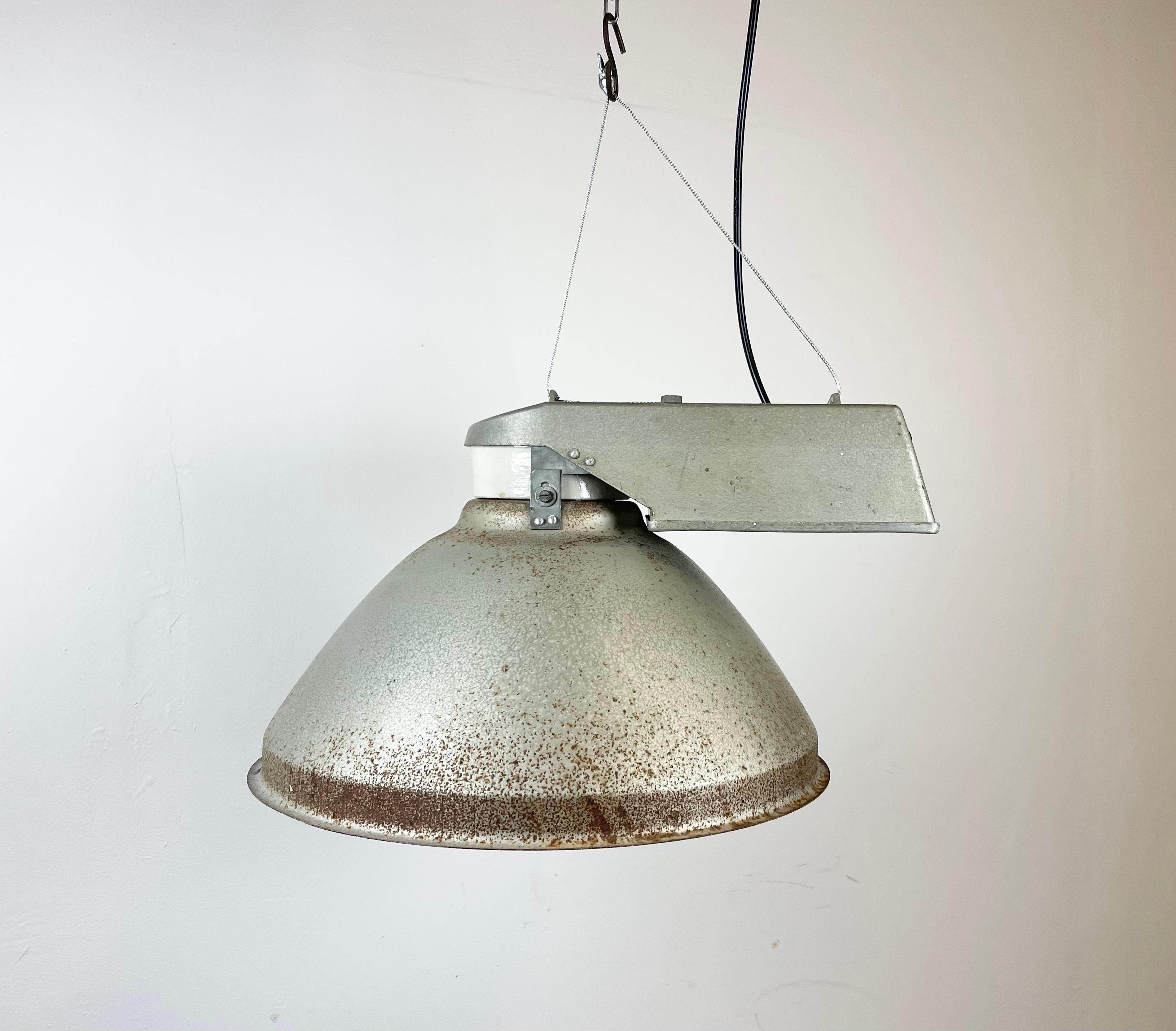 Vintage industrial hanging lamp manufactured in 1970s by MESKO in Skarzysko-Kamienna in Poland. It features a grey iron lampshade,a cast aluminium top and frosted glass cover. The porcelain socket requires E 27/ E26 light bulbs. New wire. The weight
