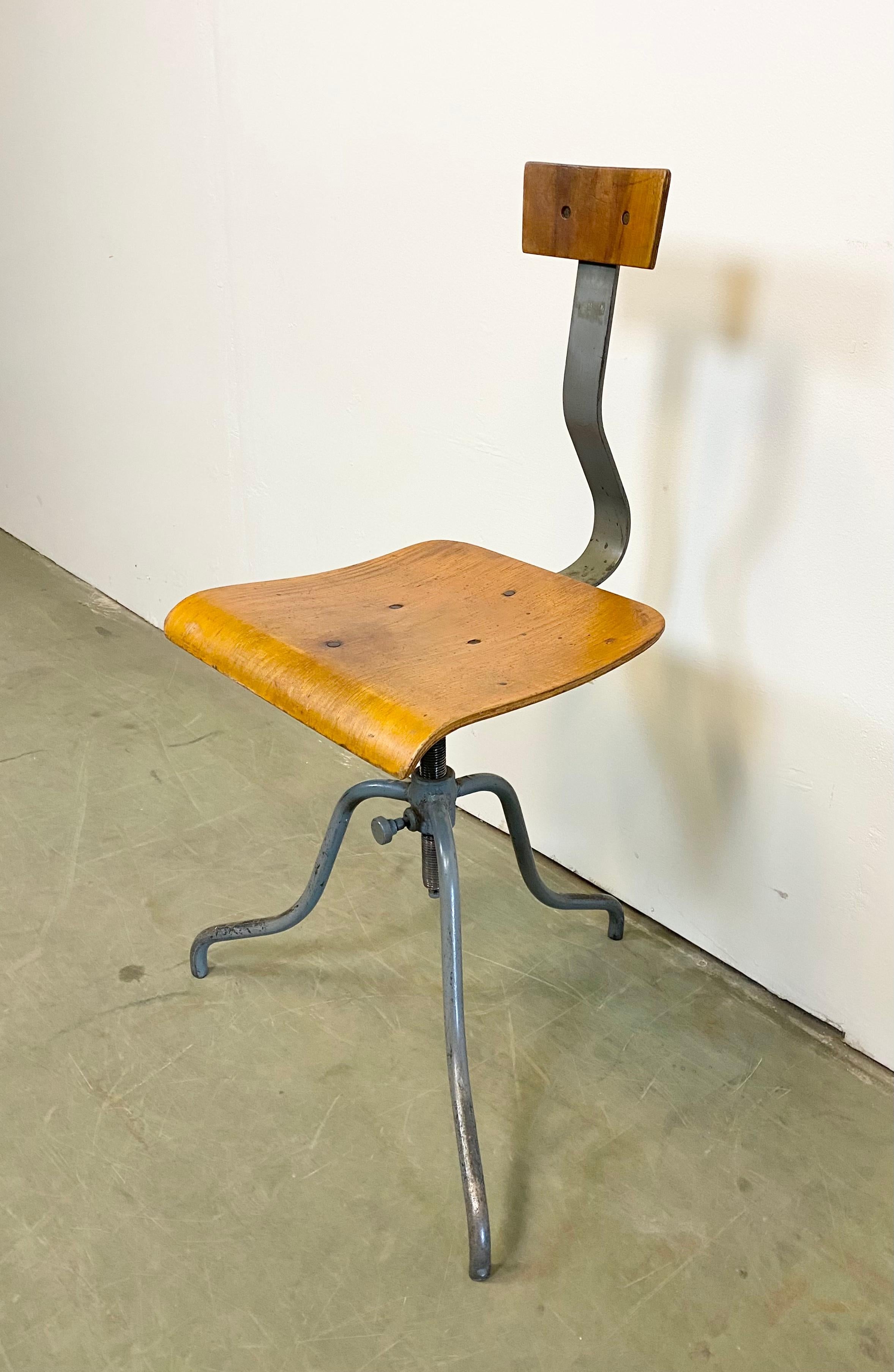 Industrial height adjustable swivel chair made in former Czechoslovakia during the 1960s. The construction is made of gray painted iron and has a plywood seat and backrest. The chair is in very good vintage condition. The weight of the chair is 8