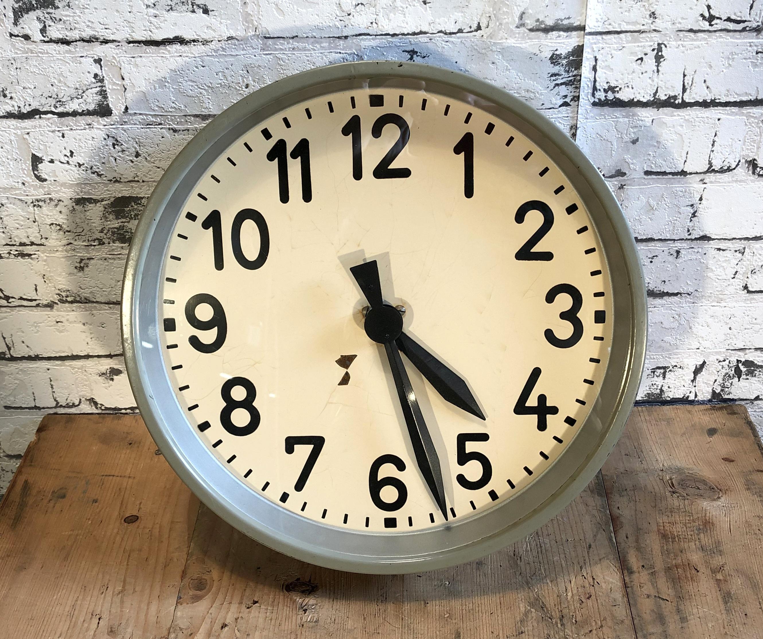 Industrial factory wall clock produced during the 1950s. The piece features a grey metal frame, iron dial and a clear glass cover. The piece has been converted into a battery-powered clockwork and requires only one AA-battery.