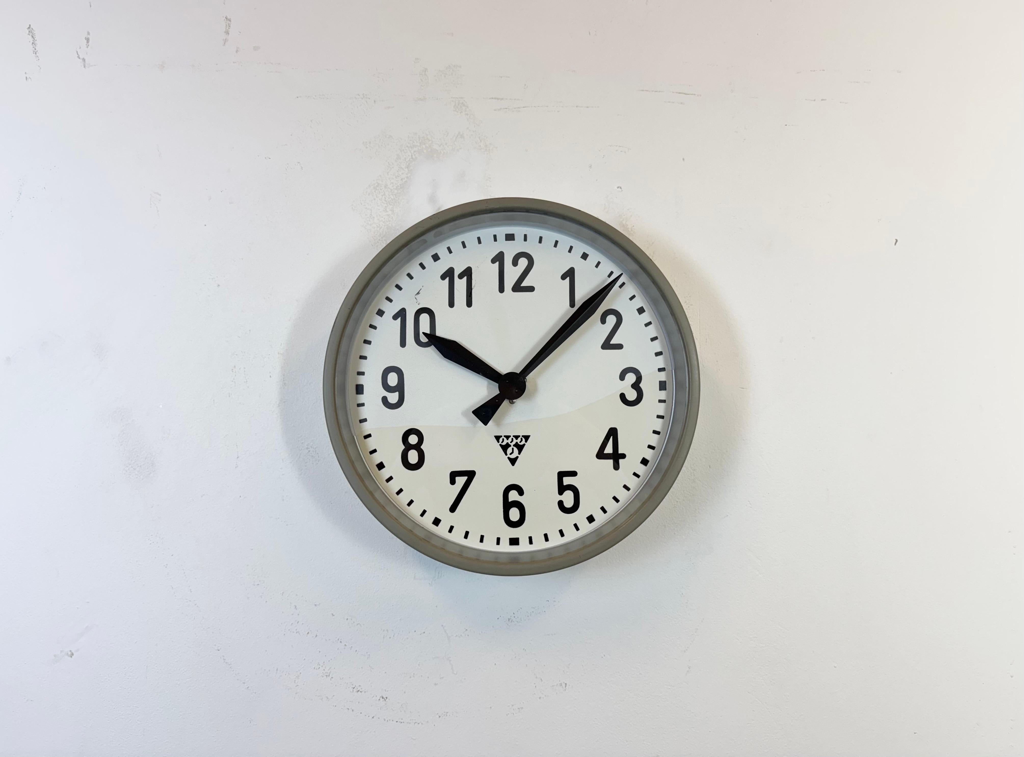 Cette horloge murale a été produite par Pragotron dans l'ancienne Tchécoslovaquie au cours des années 1960. Elle se compose d'un cadre en métal gris, d'un cadran en fer, d'aiguilles en aluminium et d'un couvercle en verre transparent. La pièce a été