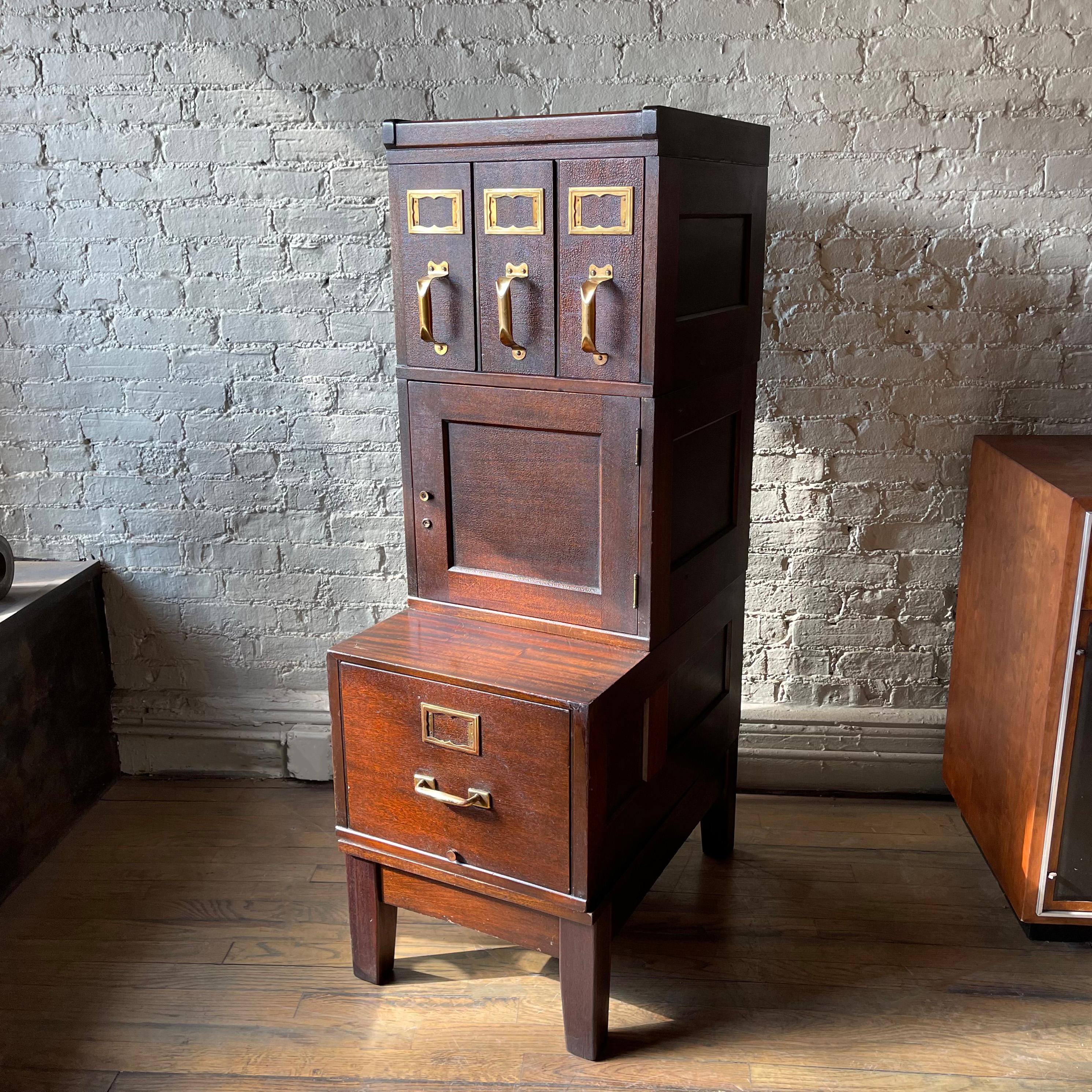 Early 20th century, industrial, document filing cabinet by Shaw Walker is comprosed of 5 flame mahogany, modular pieces; lateral filing cabinet, document safe, and file cabinet with legs and crown, with brass label plates and handles. The recessed