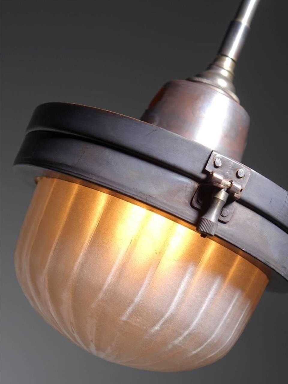 This is an interesting and very unique looking lamp. The fixture itself has a hinged copper body with locking hardware. The glass is a nice frosted and ribbed glass dome. Our design inspiration came from early railroad car ceiling flush mounts. I