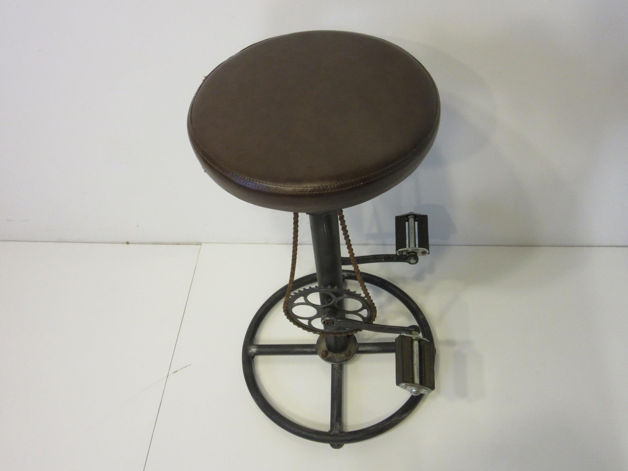 A fun Folk Art industrial stool with painted metal base and shaft having swiveling leatherette seat and a bicycle sprocket, chain and fixed pedals as foot rests. A nice unique piece for that corner of the kitchen, office or bar area.