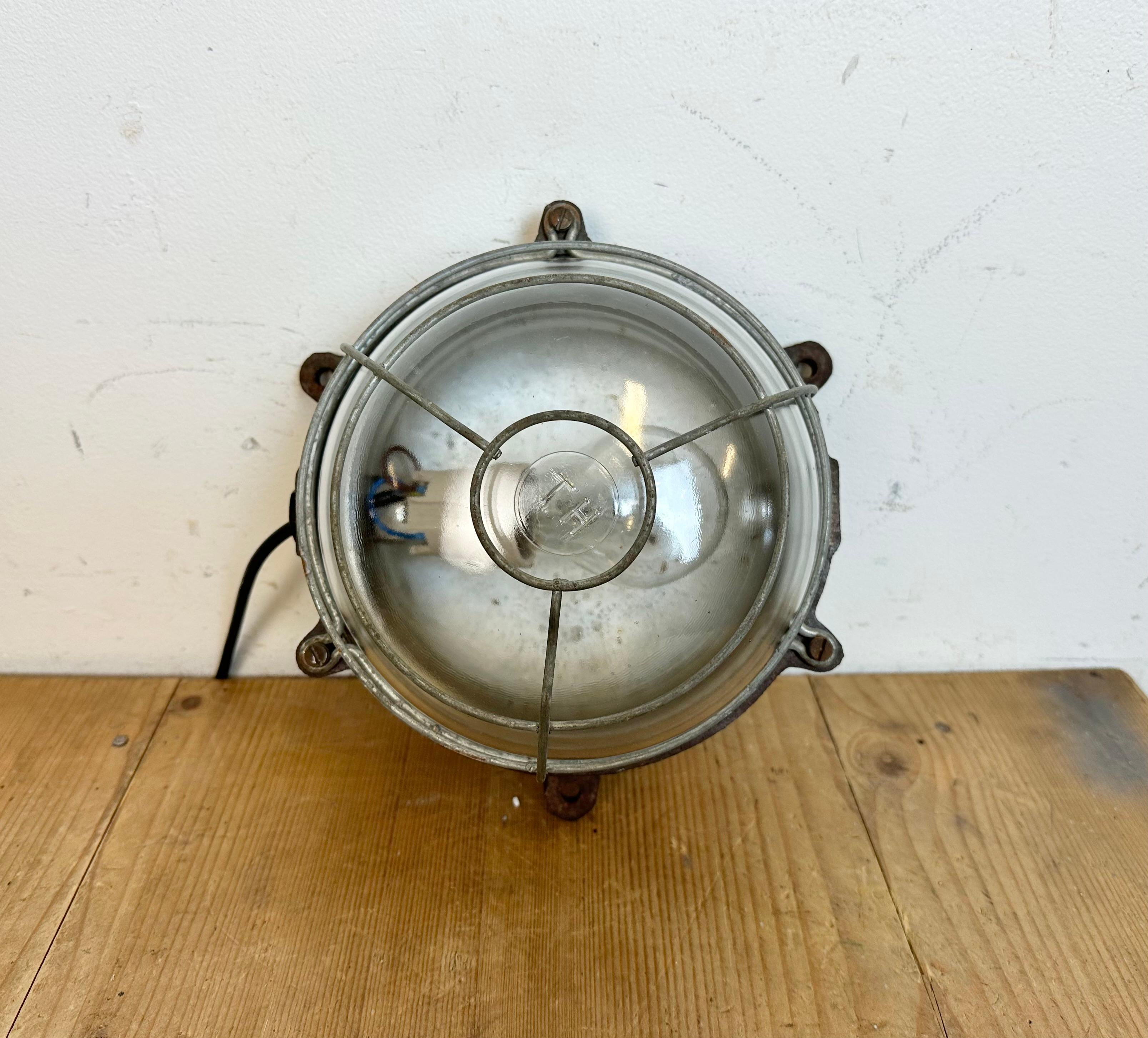 Industrial wall light made in France during the 1950s. Embossed TH brand .It features a cast iron body, a clear glass cover and a steel protectiv grid. The porcelain socket requires standard E 27/ E 26 light bulbs. New wire. The weight of the light