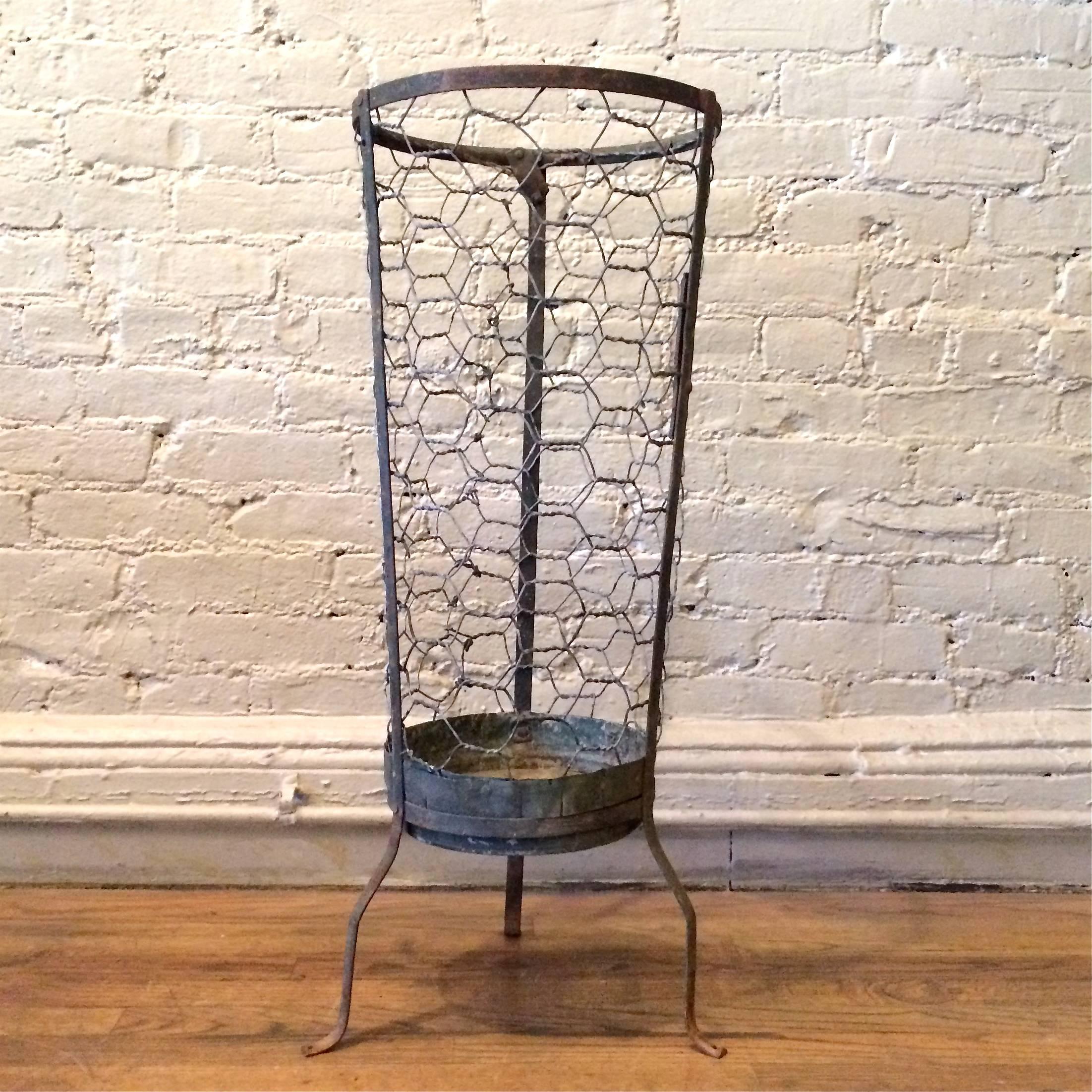 Industrial, galvanized steel, open weave, metal mesh basket with three prong base. The basket alone is 23 inches height and tapers from 9 inches at bottom to 12 inches on top. Footprint is 13 inches wide.