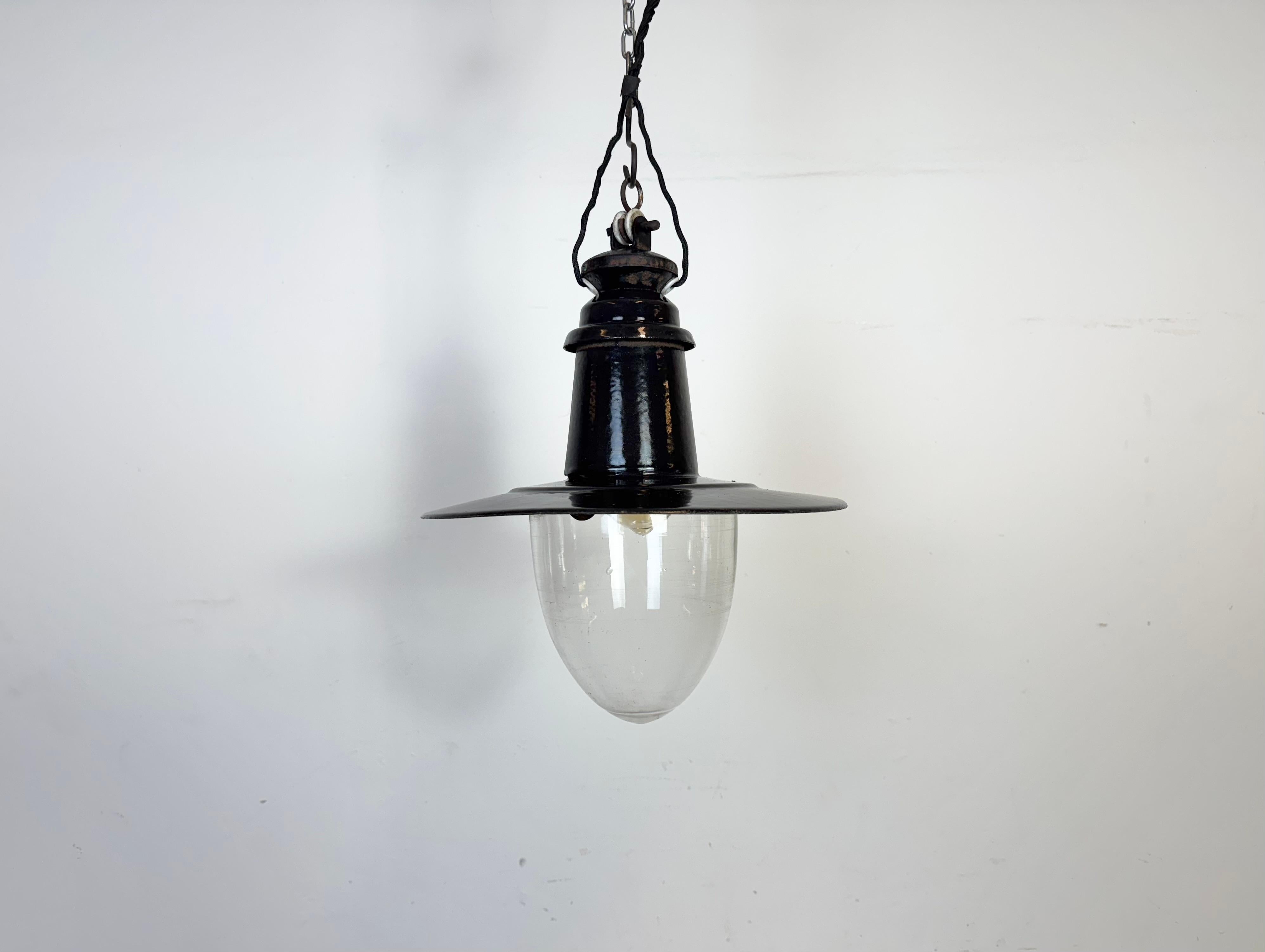 Industrial black enamel pendant light made in German during the 1930s. White enamel inside the shade. Cast iron top. Clear glass cover. The socket requires standrd E27/E26 light bulbs. New wire. The weight of the lamp is 1,7 kg.The diameter of the
