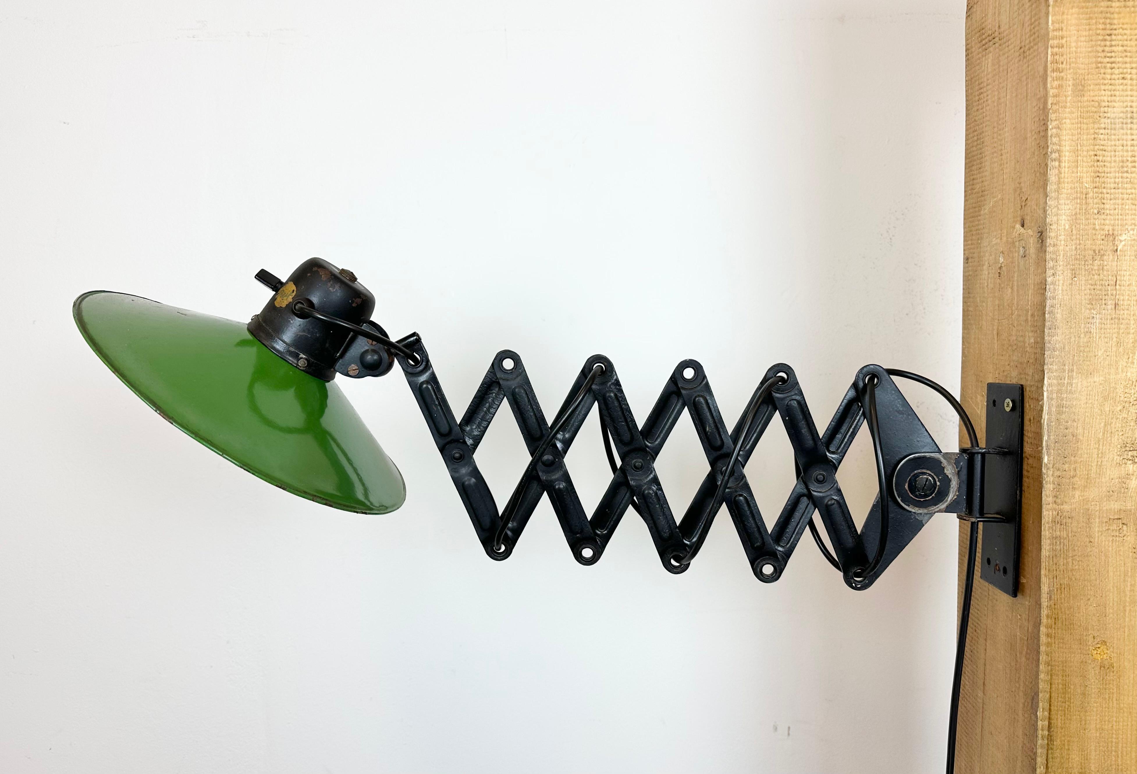 This vintage industrial scissor lamp was produced by REIF DRESDEN in Germany during the 1930s. The lamp has a green enamel shade with white enamel interior. Black iron scissor arm is extendable and can be turned sideways. The original socket with