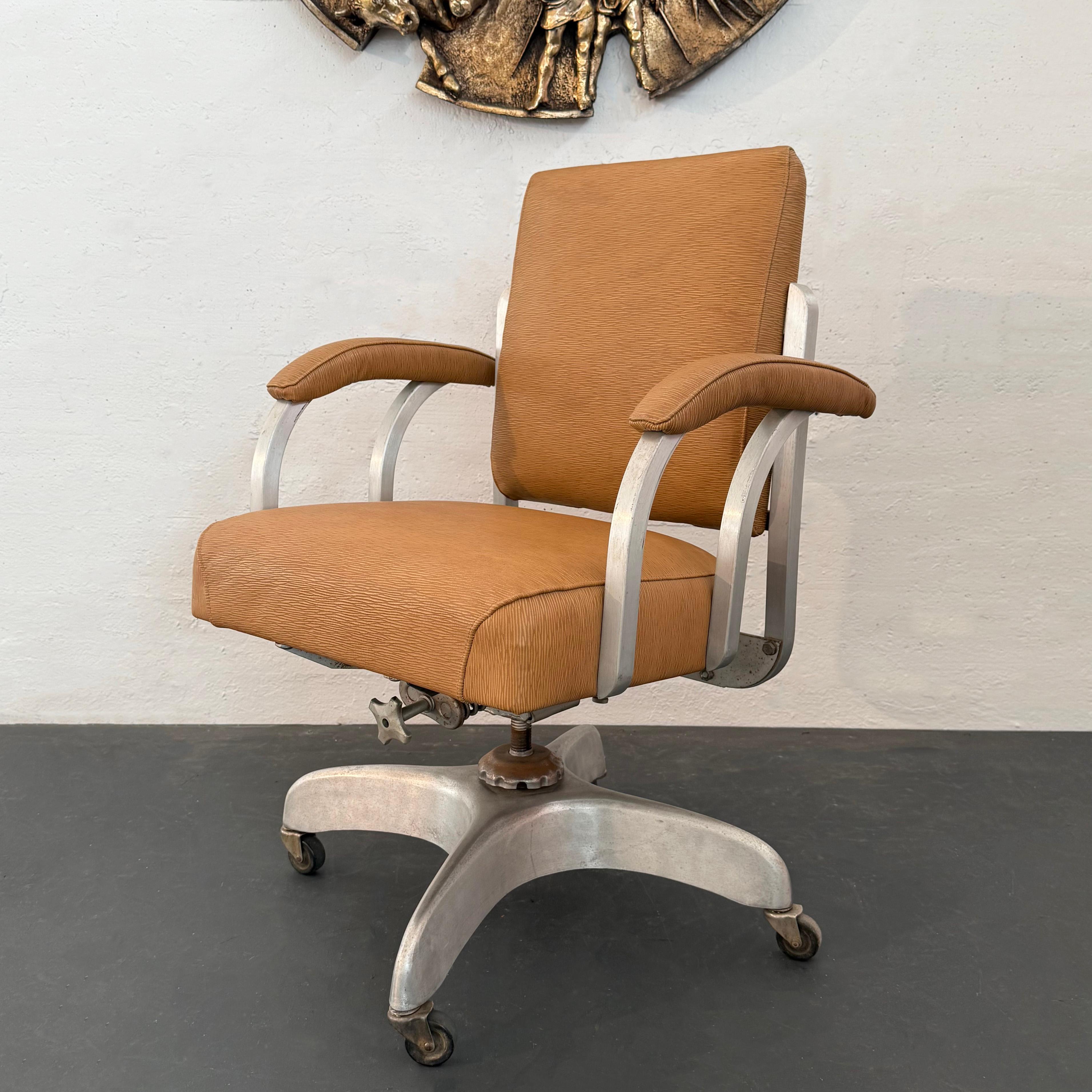 Este estilizado sillón giratorio de aluminio fue diseñado en la década de 1930 por GoodForm. El modelo es el 3129 Comfort Master. La silla tiene reposabrazos de tubo cuadrado de aluminio y una base de aluminio fundido. Para una comodidad máxima, la