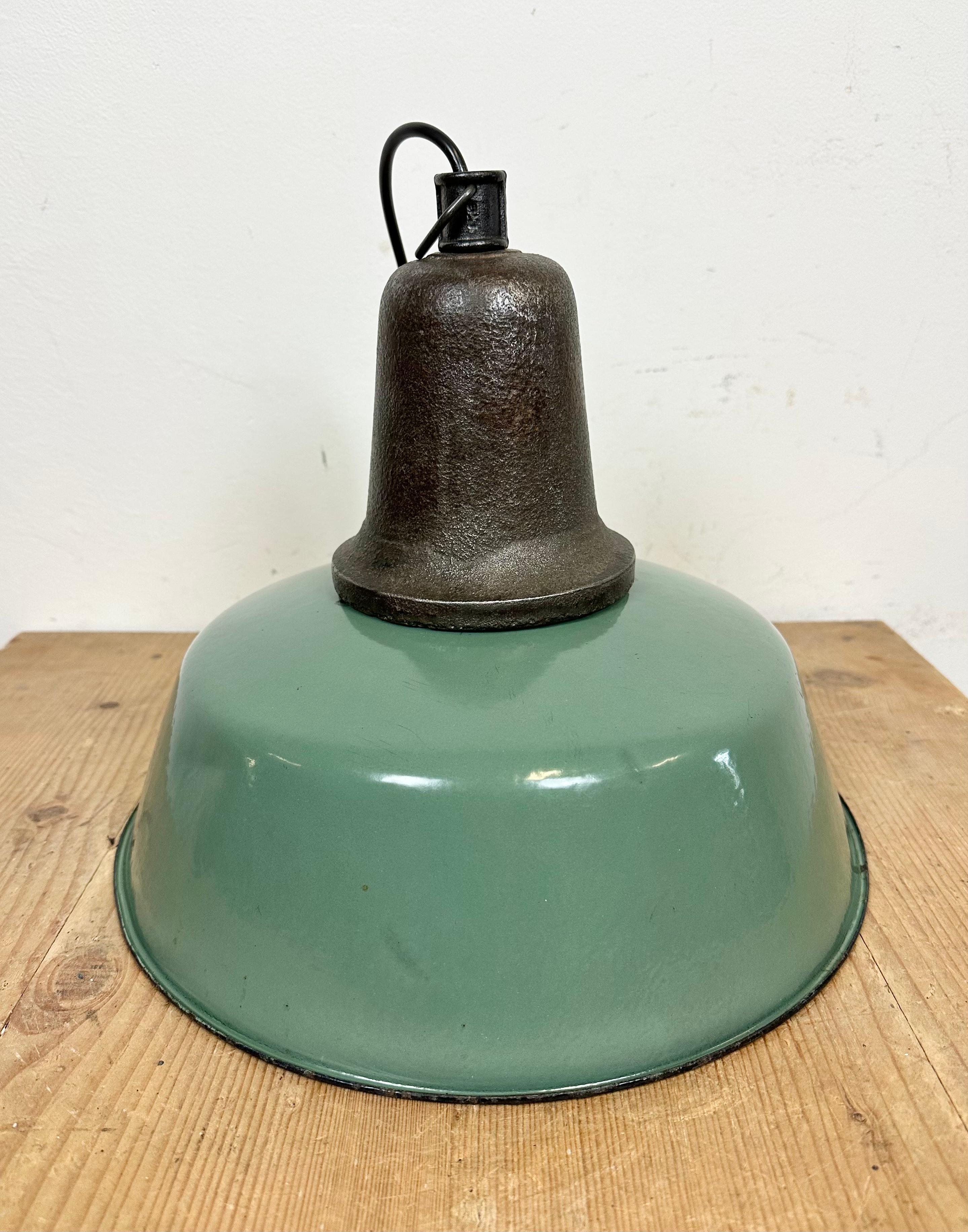 Industrial green enamel pendant light made in Poland during the 1960s. White enamel inside the shade. Cast iron top. The porcelain socket requires E 27/ E26 light bulbs. New wire. Fully functional. The weight of the lamp is 2.5 kg.