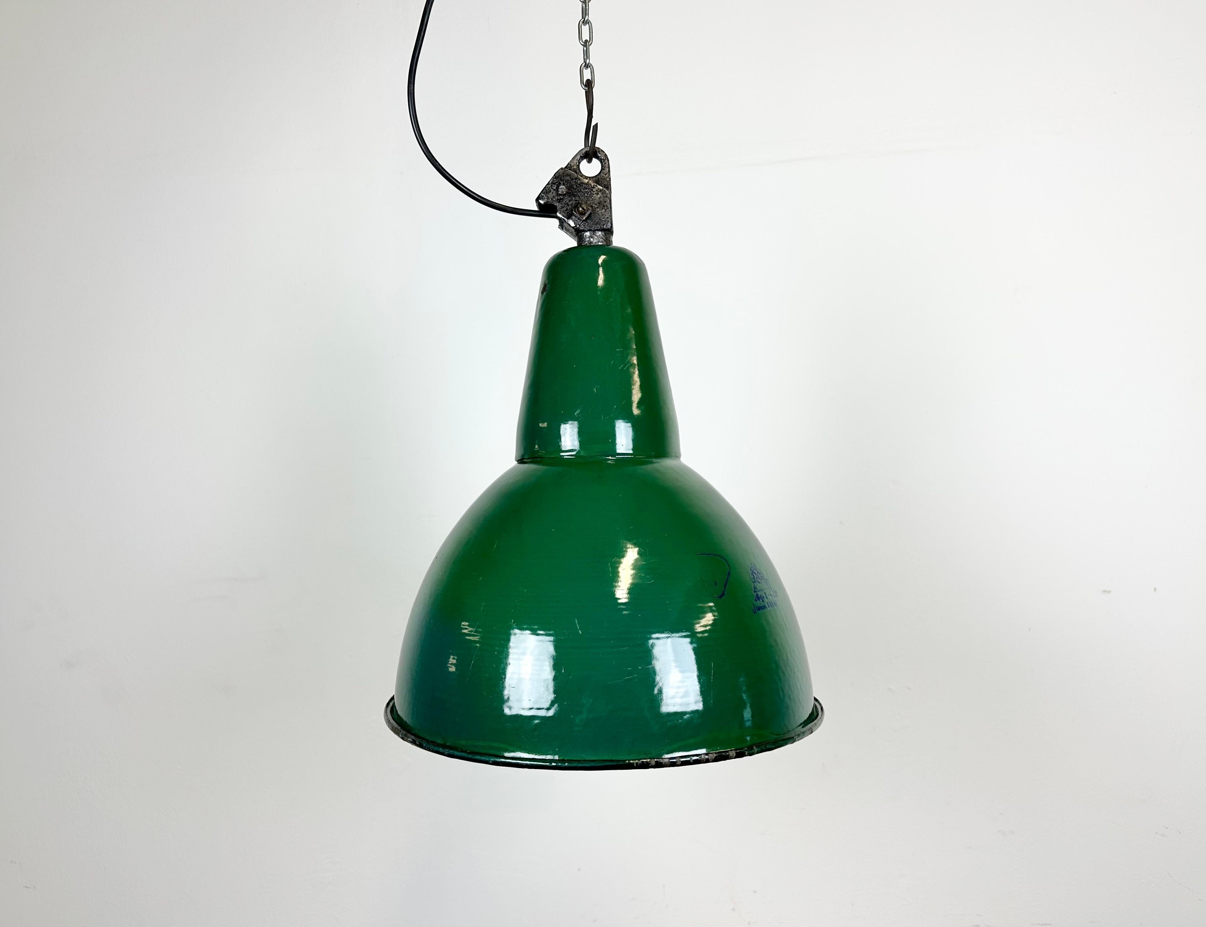 Industrial green enamel pendant light made by Polam Wilkasy in Poland during the 1960s. White enamel inside the shade. Cast iron top. The porcelain socket requires E 27/ E 26 light bulbs. New wire. Fully functional. The weight of the lamp is 2 kg.
