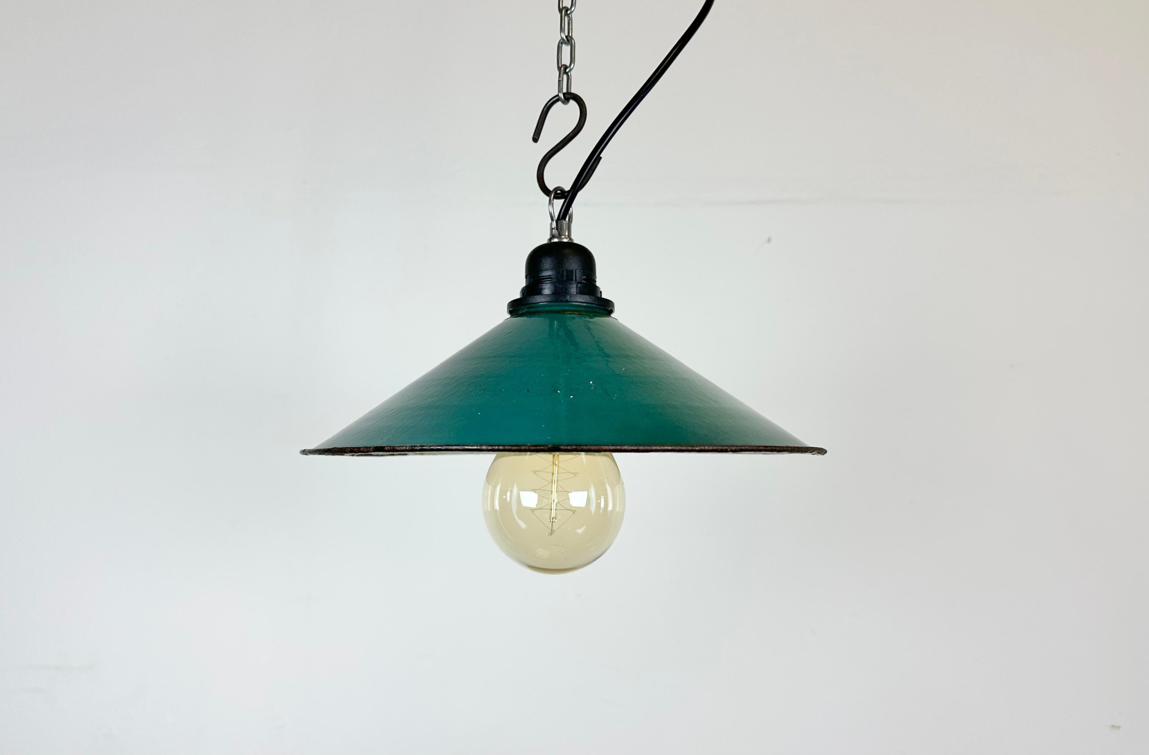 Industrial green enamel factory pendant light made in Poland during the 1960s. White enamel inside the shade. The bakelite socket with iron hook requires standard E 27/ E26 light bulbs. New wire. Fully functional. The weight of the lamp is  0,4