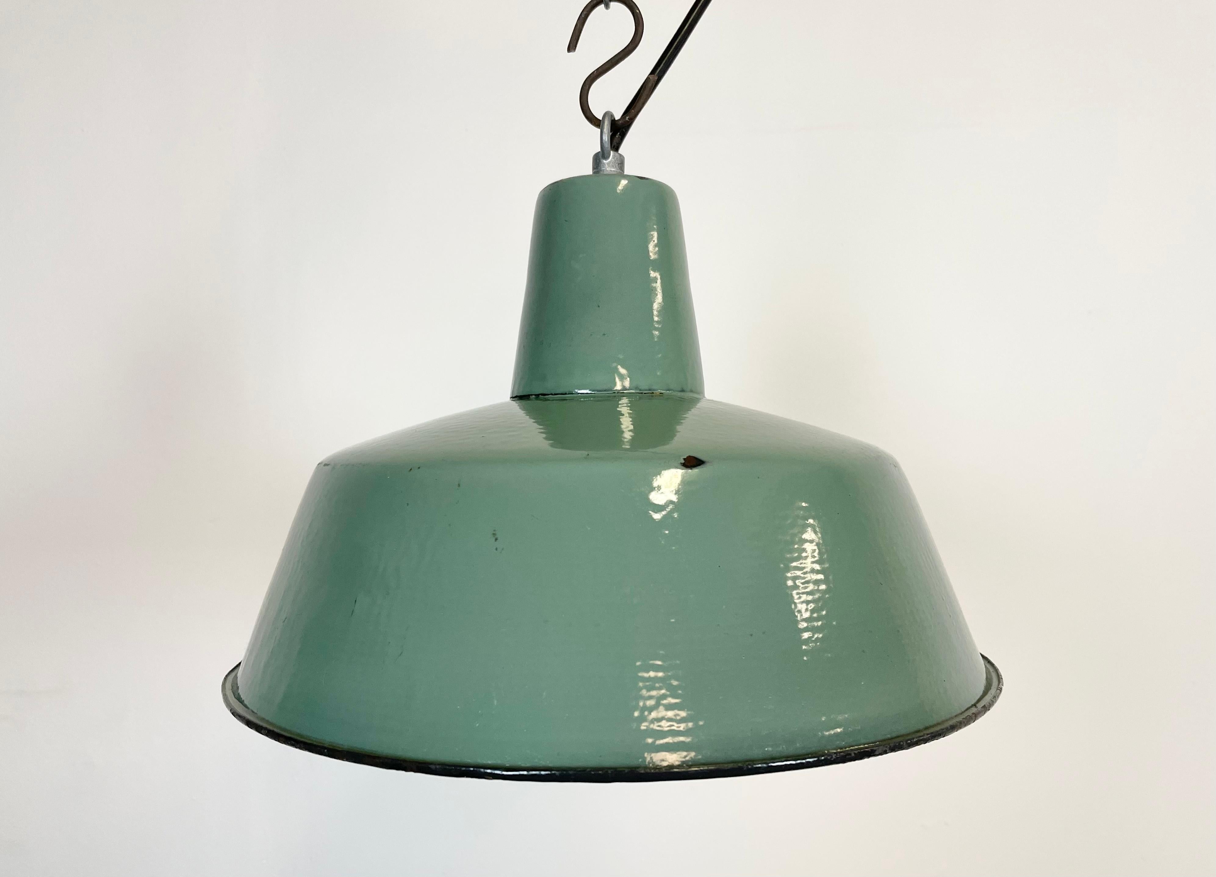 Industrial green enamel pendant light made by KWE in Poland during the 1960s. White enamel inside the shade. Iron top. The porcelain socket requires E 27 light bulbs. New wire. Fully functional. The weight of the lamp is 1,2 kg.