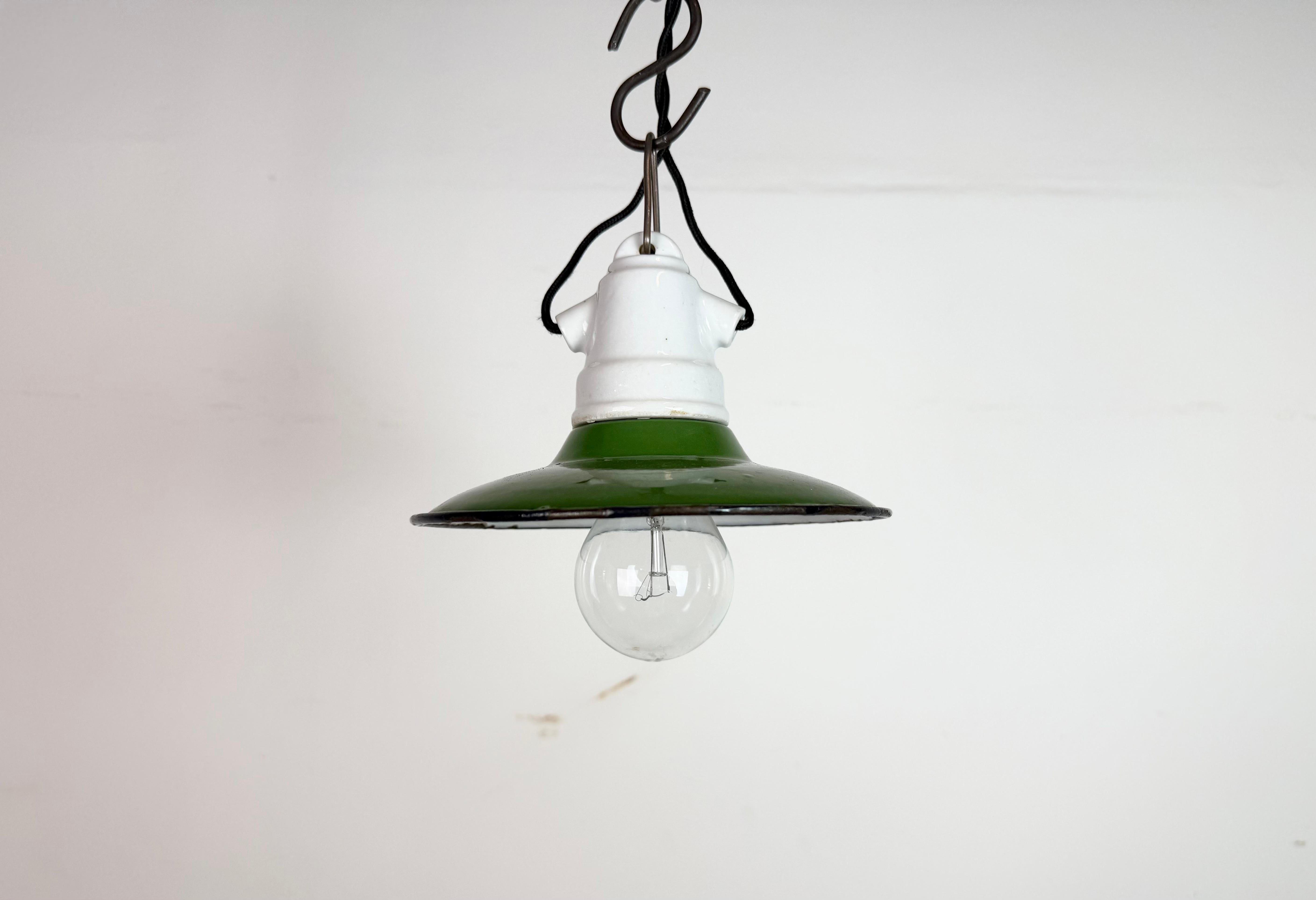 Lampada a sospensione industriale d'epoca in smalto, realizzata nell'ex Cecoslovacchia negli anni '50. Presenta un paralume in smalto verde, un interno in smalto bianco e un piano in porcellana. La presa richiede lampadine standard E 27/ E 26. Il