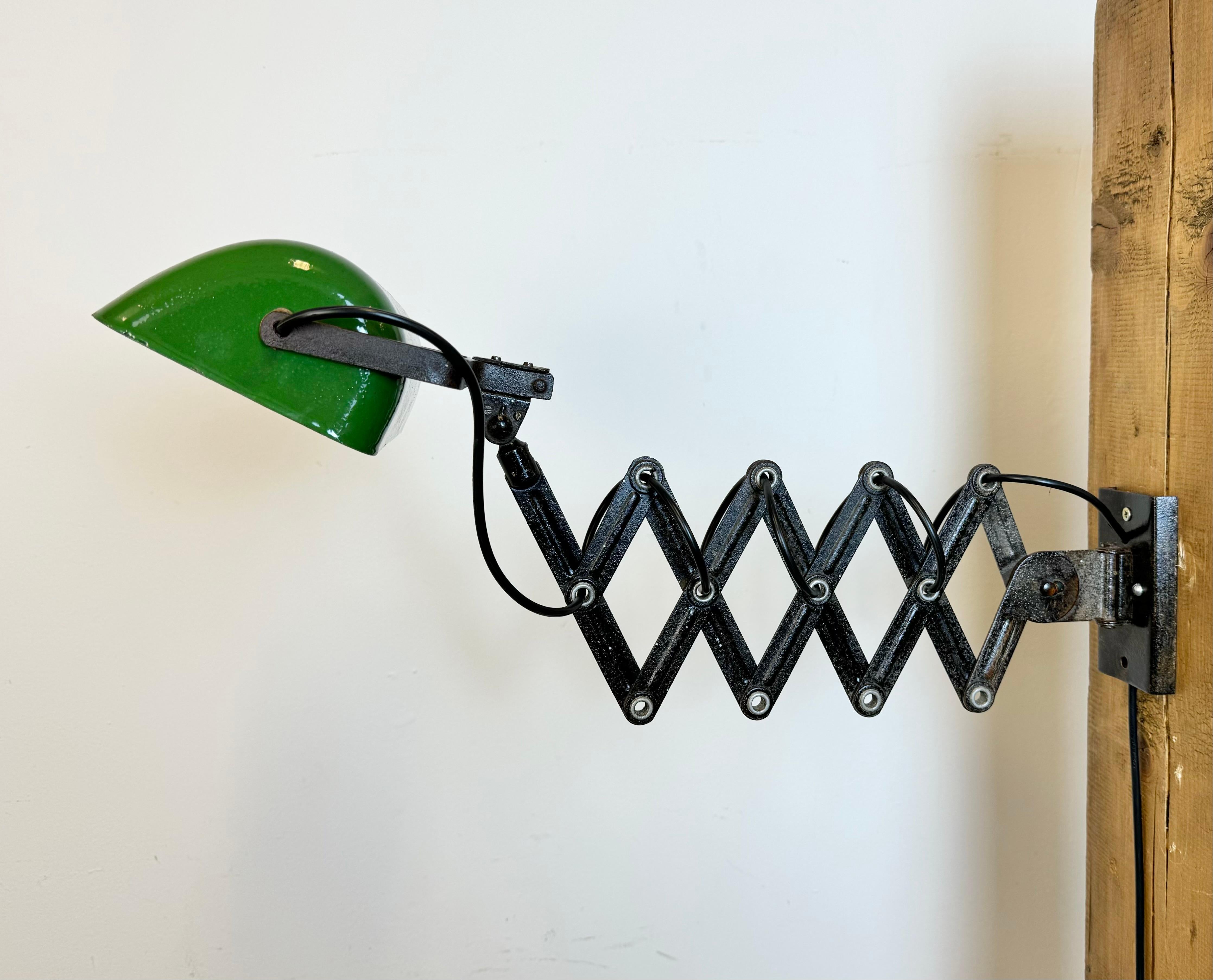 - Industrial scissor lamp was produced in former Czechoslovakia during the 1950s
- The lamp has a green enamel metal shade, white interior
- The black scissor arm is extendable and can be turned sideways
- Original porcelain socket with switch
