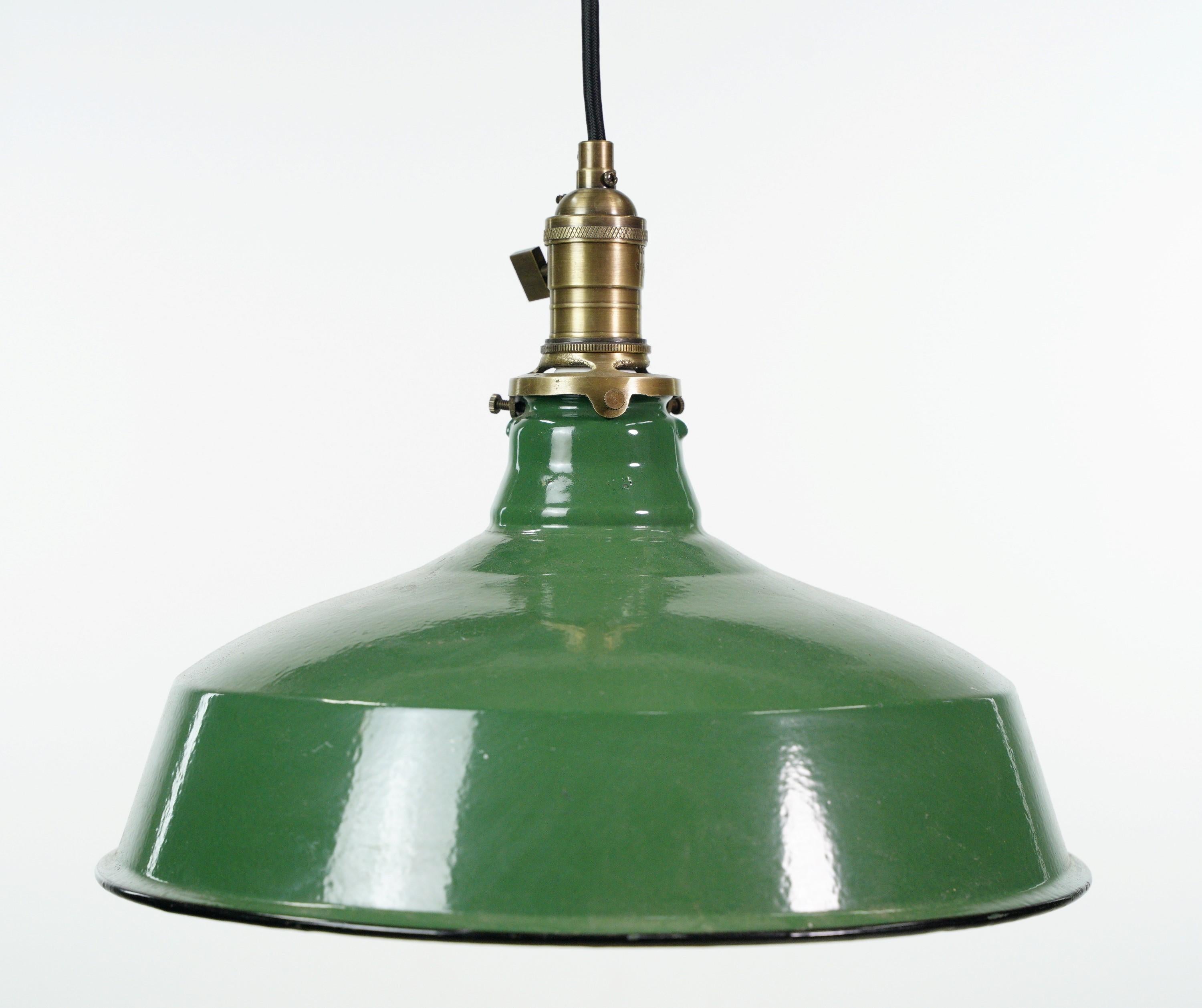 Industrial pendant light featuring a vintage green and white enameled steel shade with a newly made black cord and antique brass finished fitter. This unique blend of materials and finishes creates a bold statement piece that combines vintage charm
