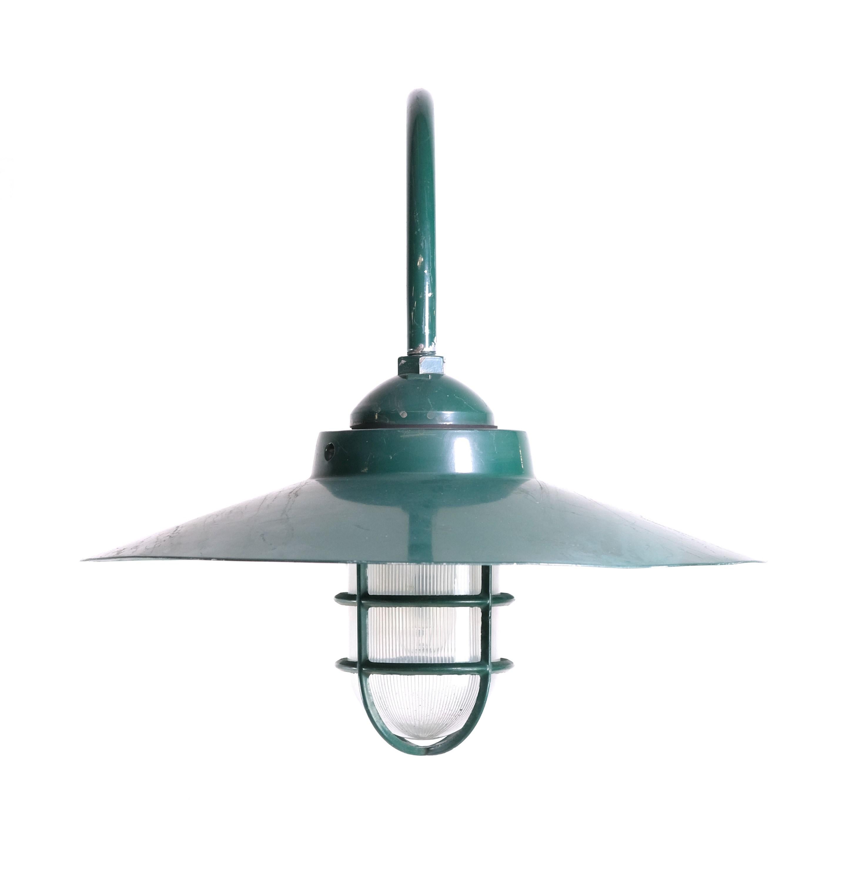 Almost new exterior wall sconce manufactured out of aluminum and steel. Light comes with a protective cage and has a ribbed glass globe. Green enamel finish. Cleaned and restored. Small quantity available at time of posting. Please inquire. Priced