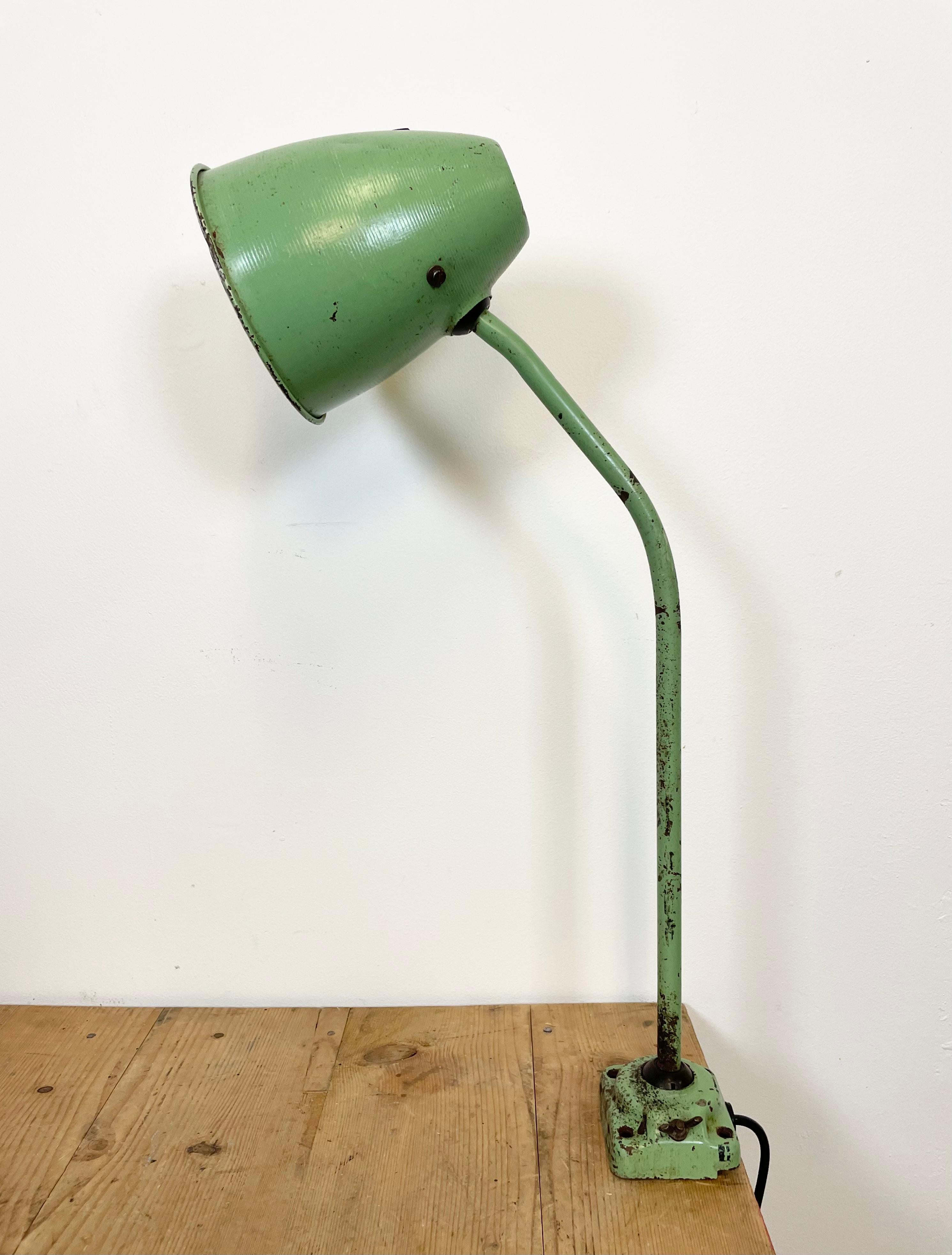 This green industrial style iron table lamp was made in former Czechoslovakia. It features an iron shade ,base and arm, two adjustable joints, a porcelain socket for E 27 light bulbs and new wire. The original switch is situated directly on the