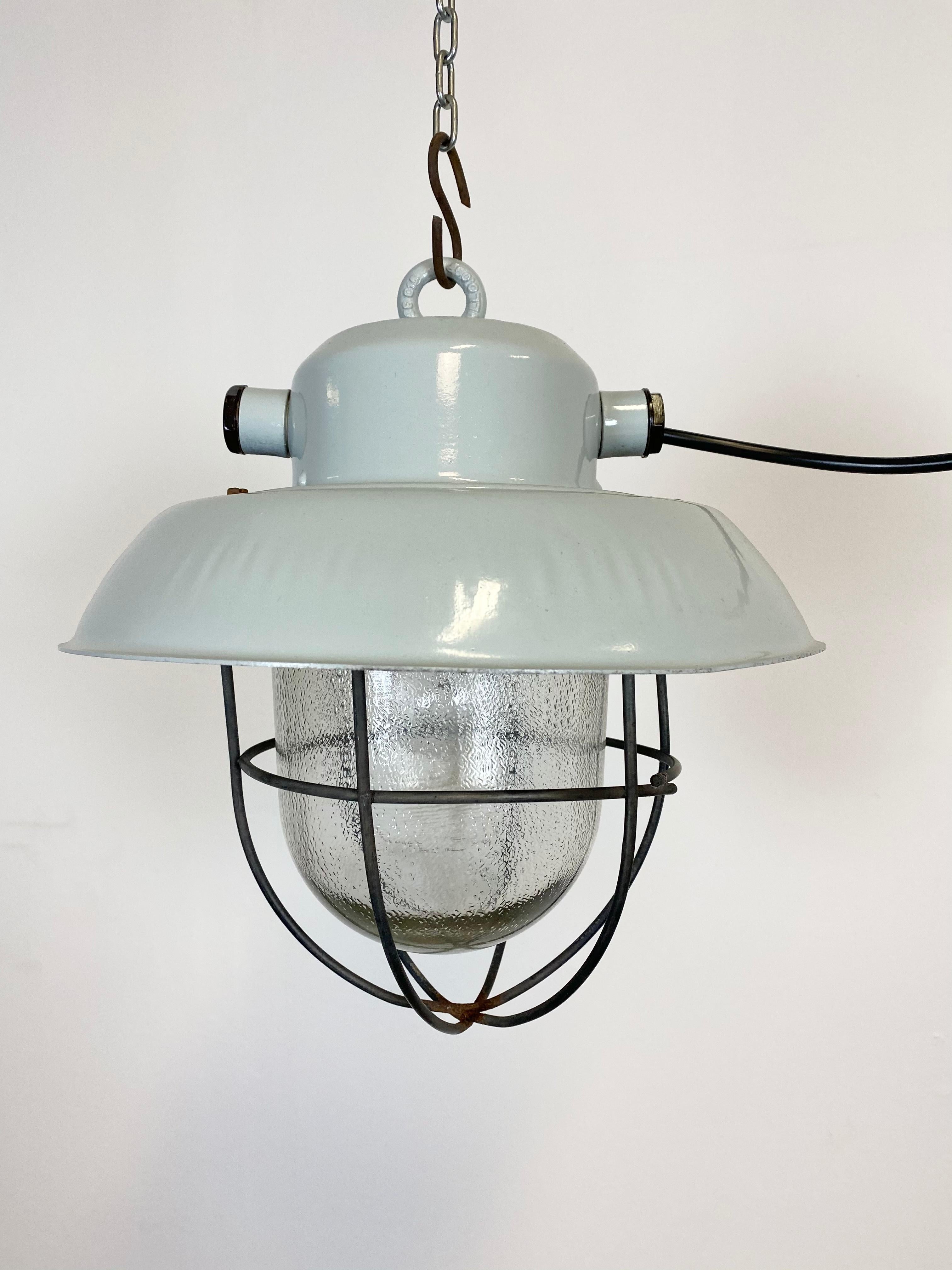 Industrial pendant lamp made in former Czechoslovakia during the 1960s.It features an aluminium shade, a frosted glass and a iron grid. New porcelain socket requires E 27 lightbulbs. New wire. The weight of the lamp is 2 kg.