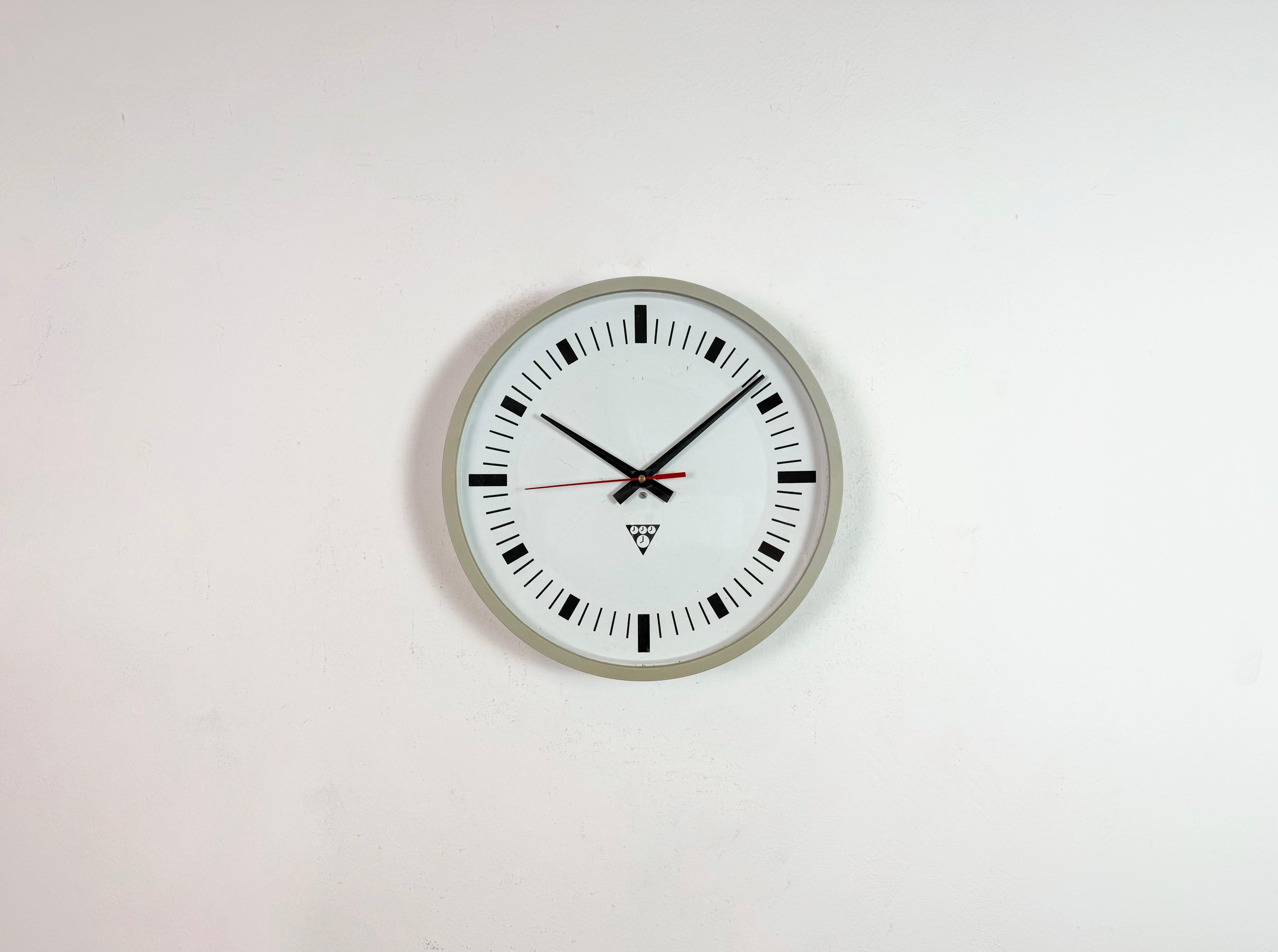 Wall clock produced by Pragotron in former Czechoslovakia during the 1970s.-1990s. The piece features a grey bakelite frame, an aluminium dial and clear glass cover. The piece has been converted into a battery-powered clockwork and requires only one