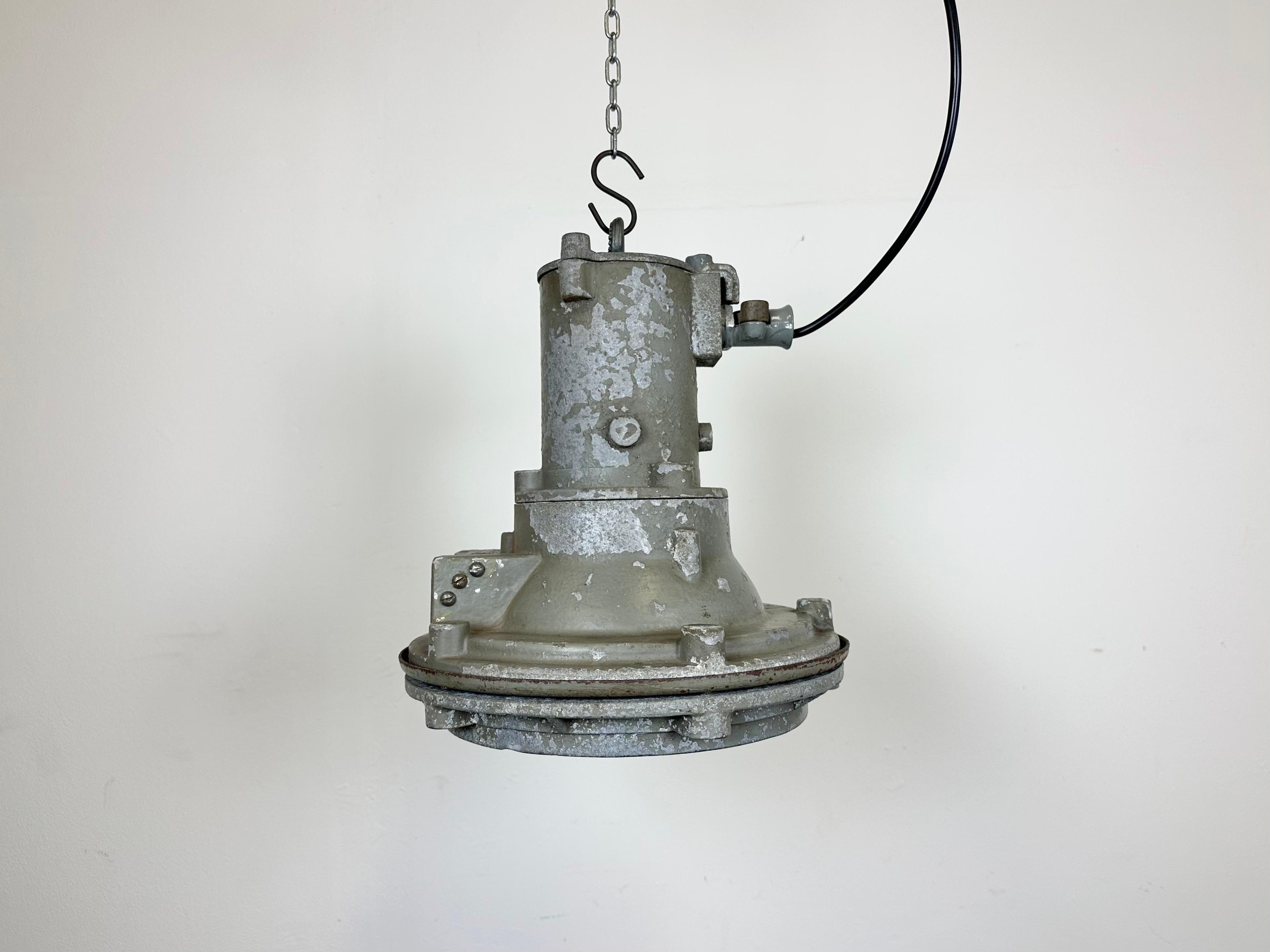 Industrial factory hanging lamp made in former Czechoslovakia during the 1960s. It features a cast aluminium body and a lens glass cover .The porcelain socket requires standard E 27/ E 26 lightbulbs. New wire. The weight of the lamp is 9 kg.The