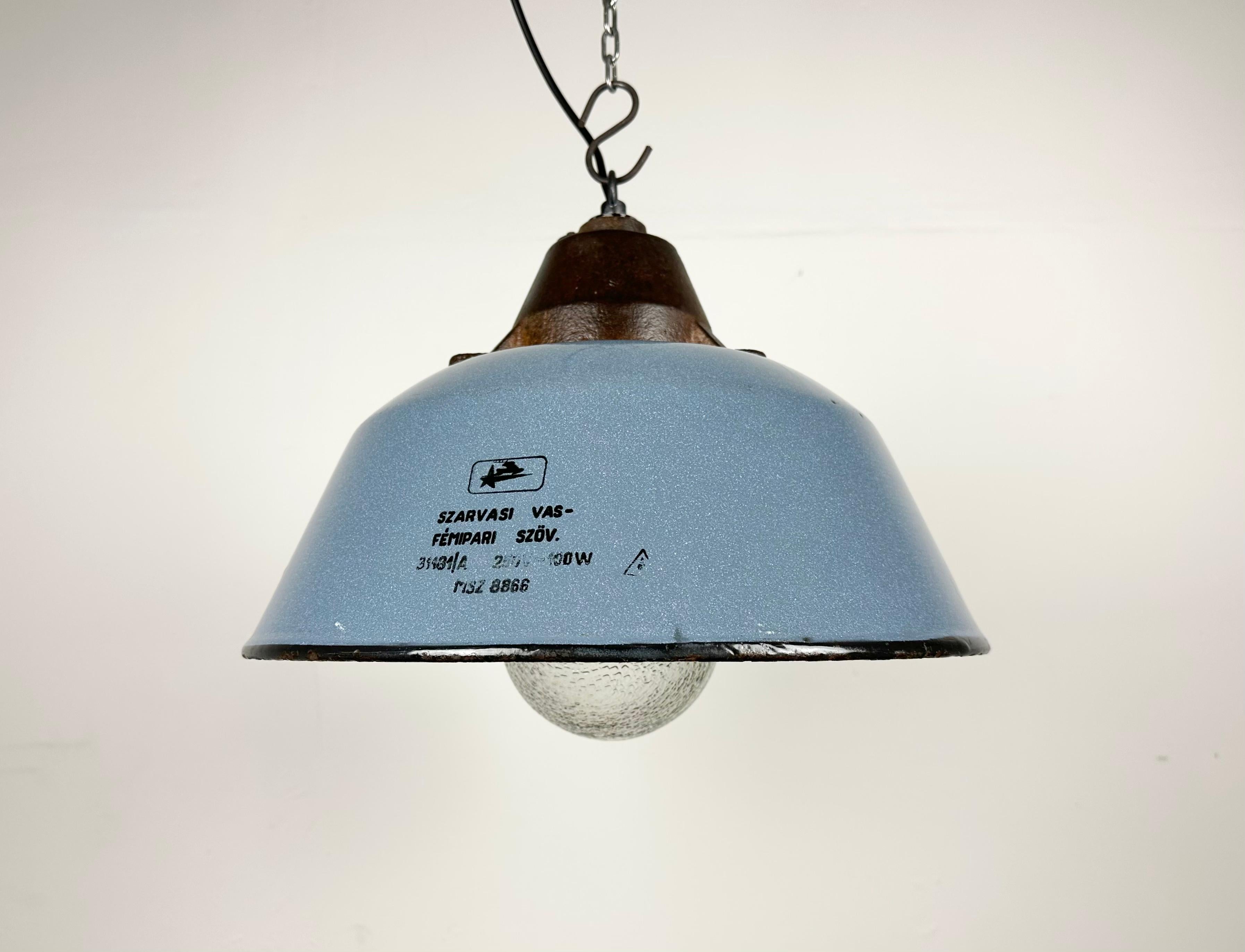 Industrial hanging lamp manufactured by Szarvasi Vas - Fém in Hungary during the 1960s. It features a grey enamel shade, a white enamel interior, a cast iron top and a frosted glass cover. New porcelain socket requires E 27/ E26 light bulbs. New