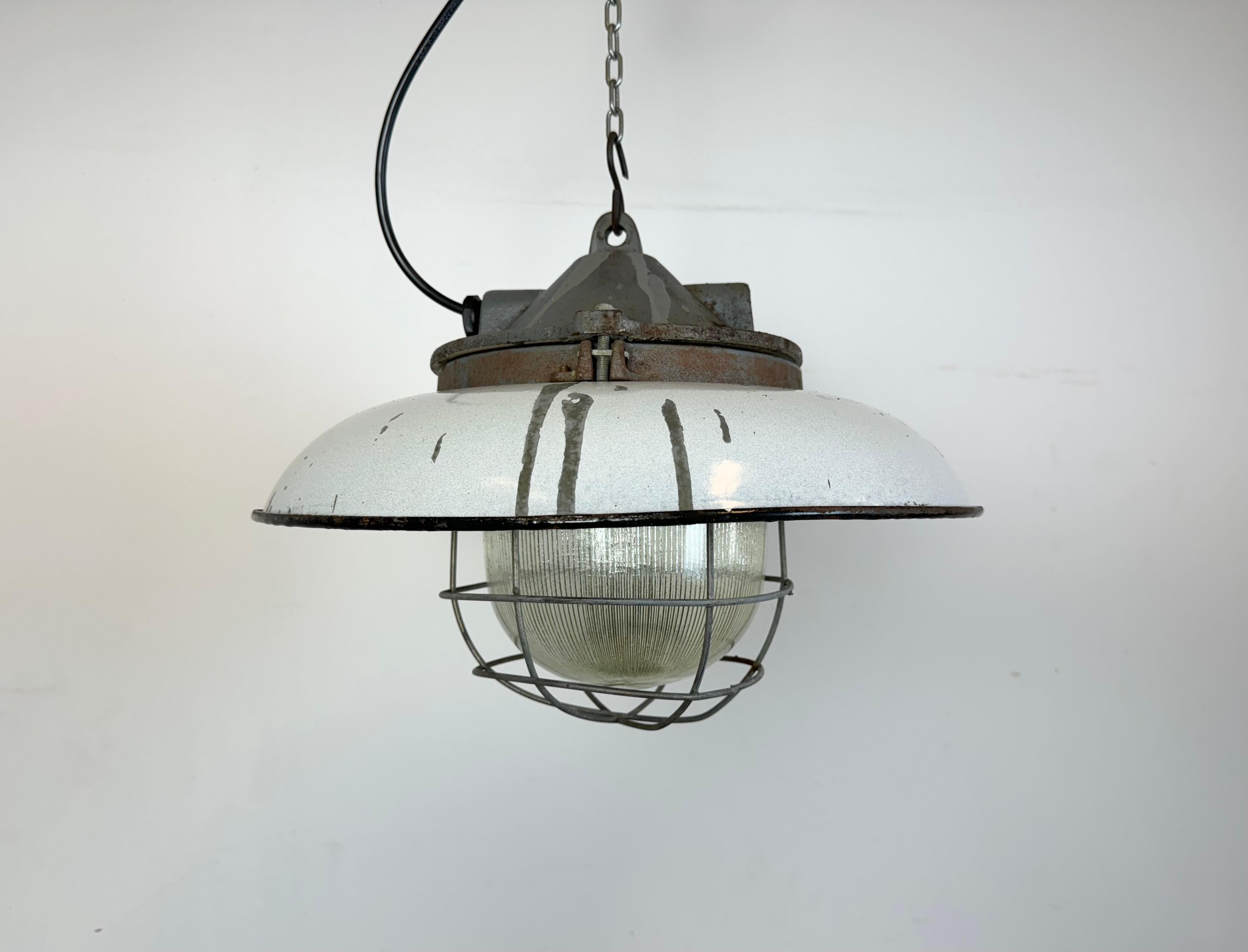 - Lampada a sospensione industriale in ghisa
- Prodotto da Zaos in Polonia negli anni '60.
- Paralume in smalto grigio chiaro con interno in smalto bianco 
- Coperchio in vetro olofane e griglia in ferro
- Peso: 7 kg
- Il diametro del paralume è di