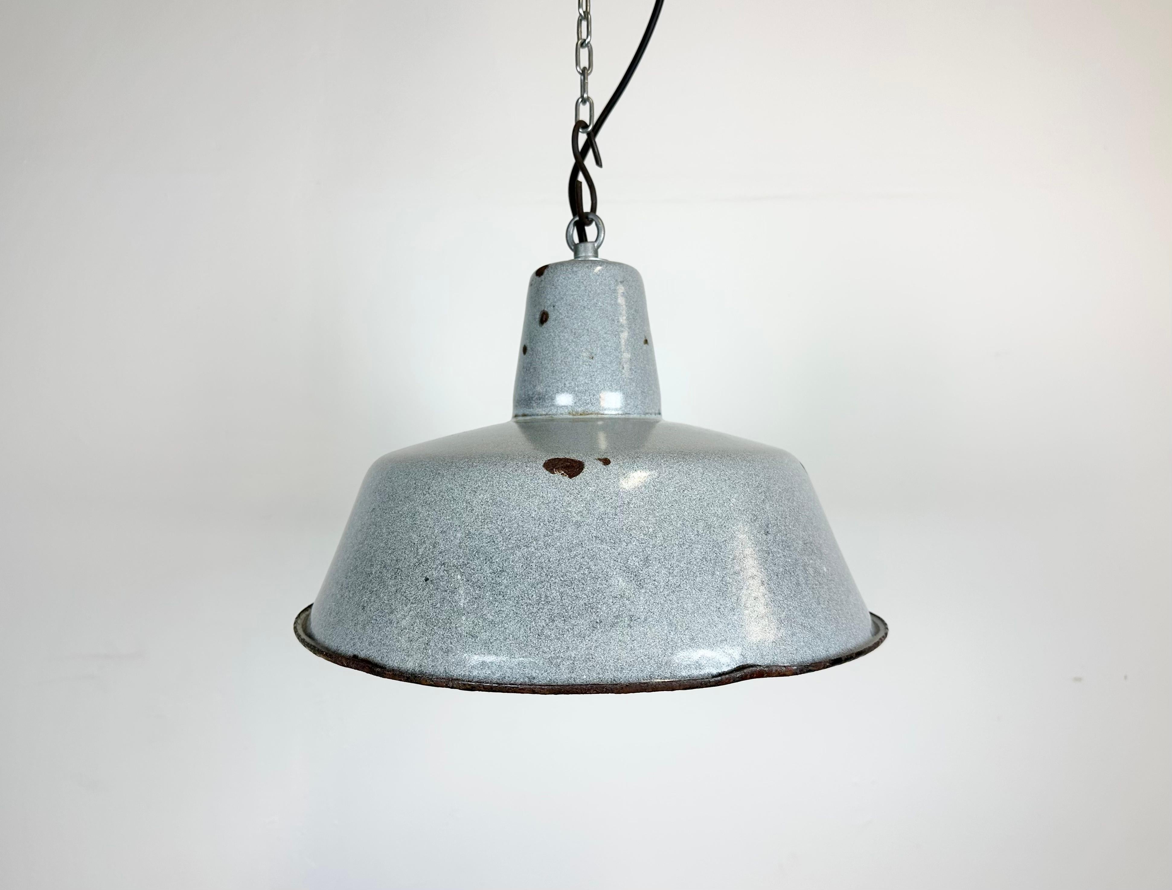 Industrial grey enamel pendant light made in Poland during the 1960s. White enamel inside the shade. Iron top. The porcelain socket requires E 27/ E 26 light bulbs. New wire. Fully functional. The weight of the lamp is 1,2 kg.