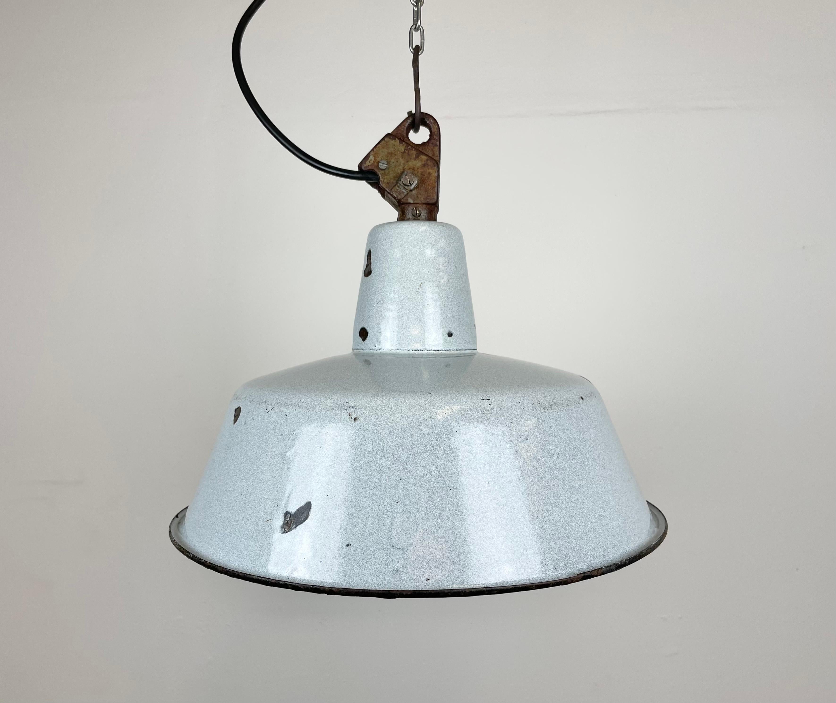Industrial grey enamel pendant light made by KWE in Poland during the 1960s. White enamel inside the shade. Cast iron top. The porcelain socket requires E 27 light bulbs. New wire. Fully functional. The weight of the lamp is 1,5 kg.