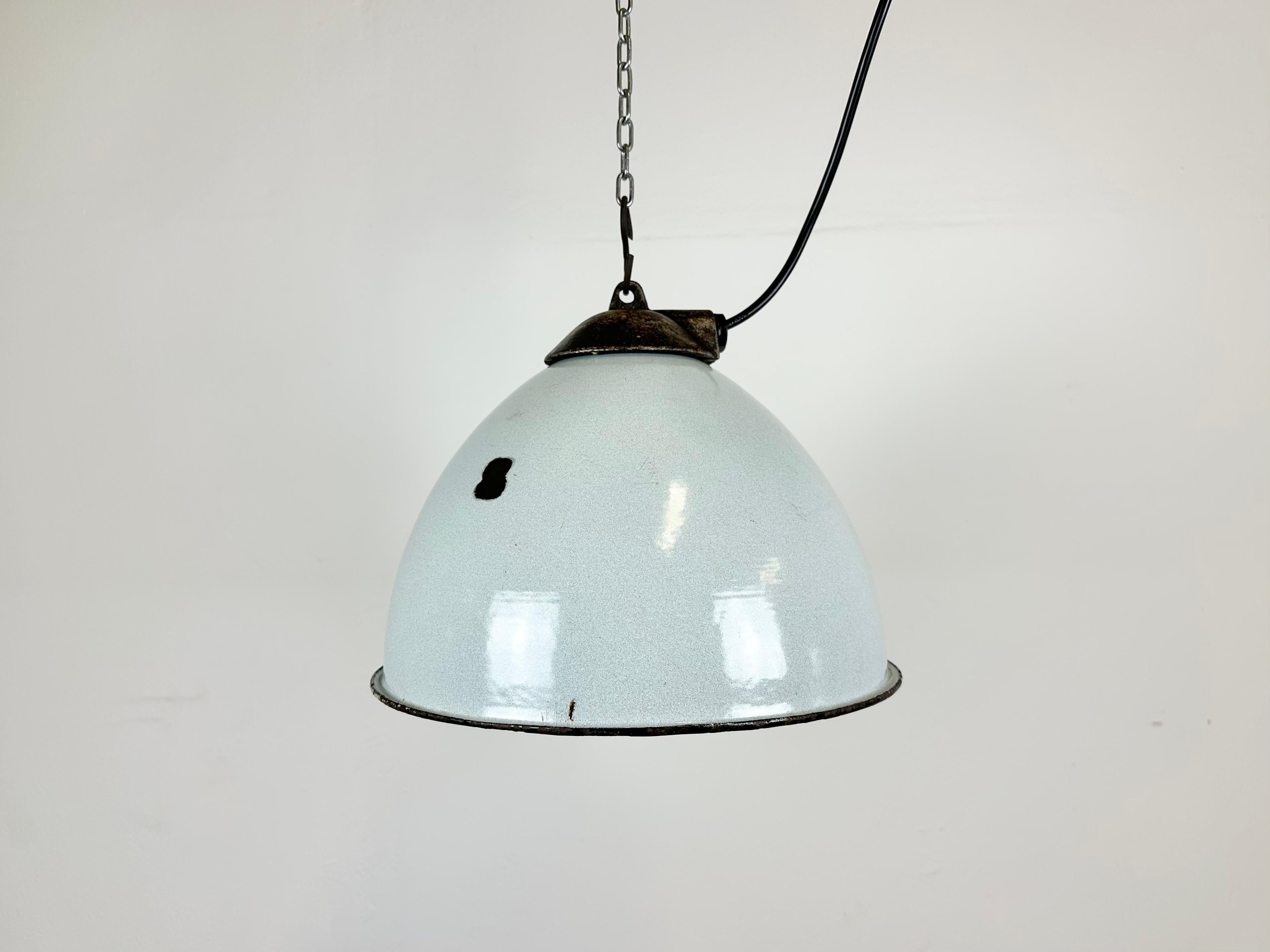 Industrial grey enamel pendant light made by Zaos in Poland during the 1960s. White enamel inside the shade. Cast iron top. The porcelain socket requires E 27/ E 26 light bulbs. New wire. Fully functional. The weight of the lamp is 1,8 kg.