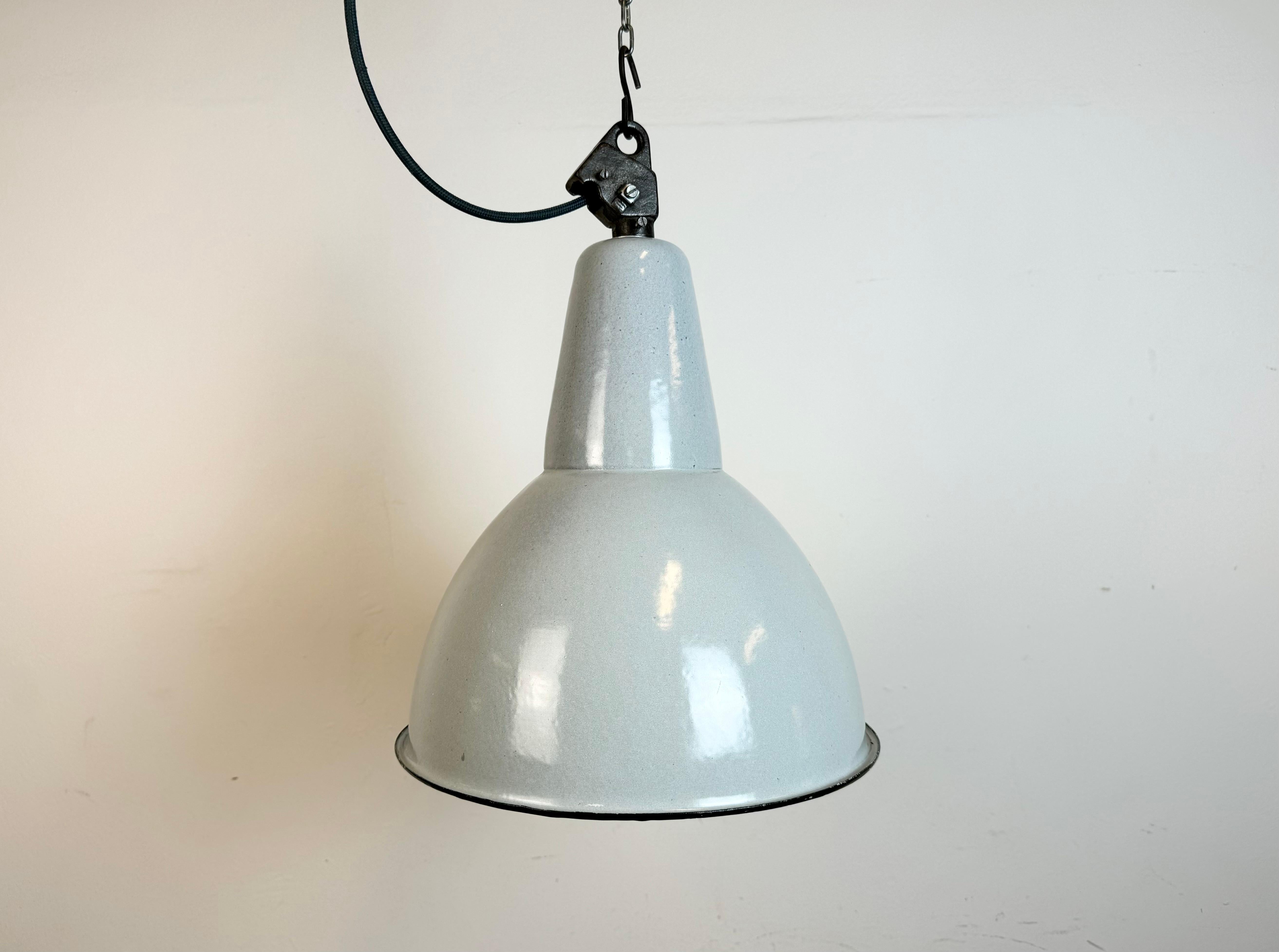 Industrial grey enamel pendant light made by A23 factory in Wilkasy in Poland during the 1960s. White enamel inside the shade. Cast iron top. The porcelain socket requires standard E 27/ E26 light bulbs. New wire. Fully functional. The weight of the