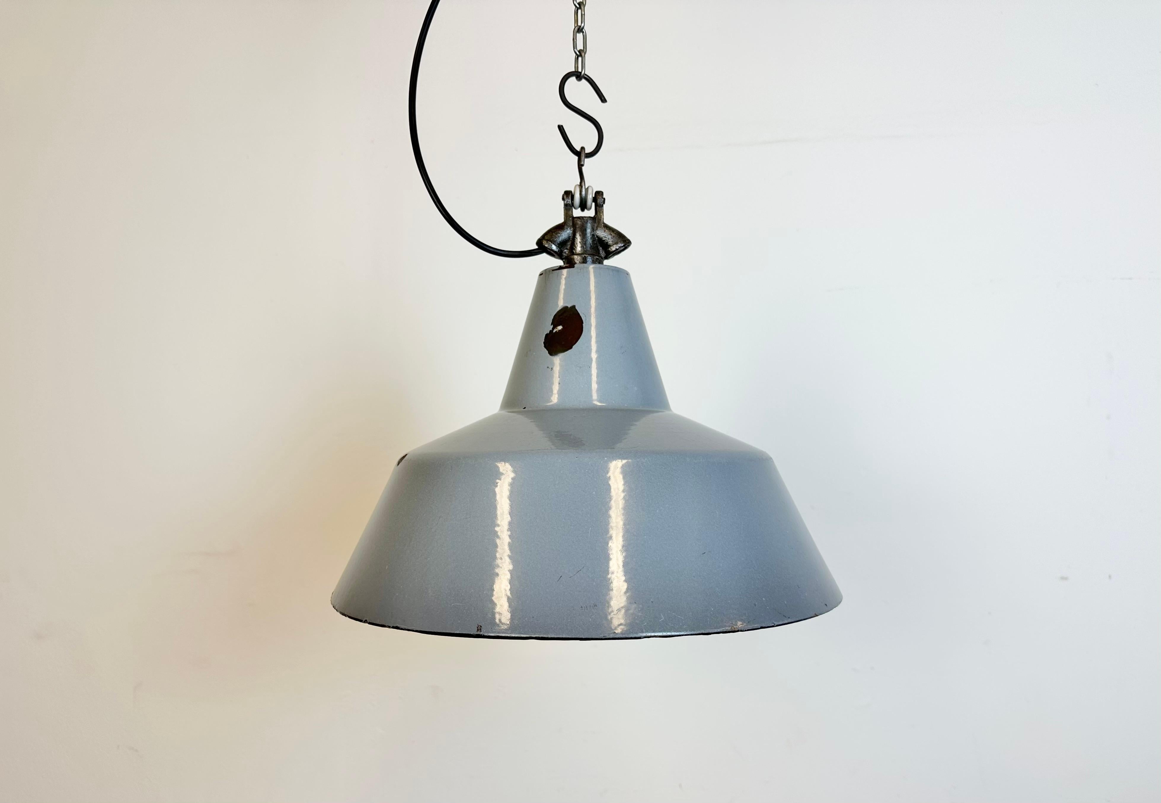 Industrial grey enamel factory pendant light made in Netherlands during the 1960s. White enamel inside the shade. Cast iron top. Porcelain socket requires standard E 27/ E26 light bulbs. New wire. Fully functional. The weight of the lamp is  1,1