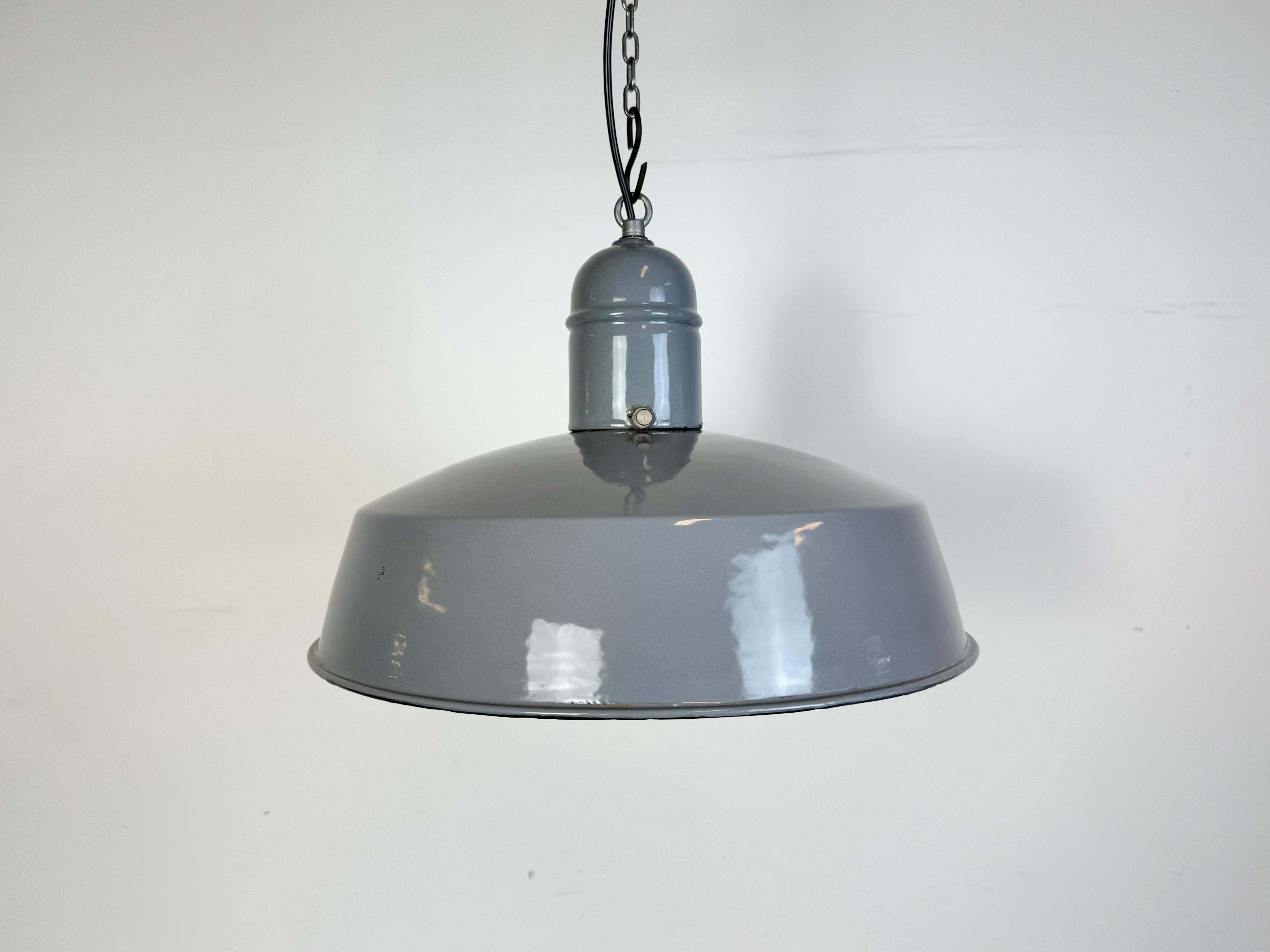 Lampada a sospensione industriale in smalto grigio prodotta nei Paesi Bassi negli anni '60. Smalto bianco all'interno del paralume. Top in ferro. L'attacco in porcellana richiede lampadine standard E 27/ E26. Un nuovo cavo. Completamente