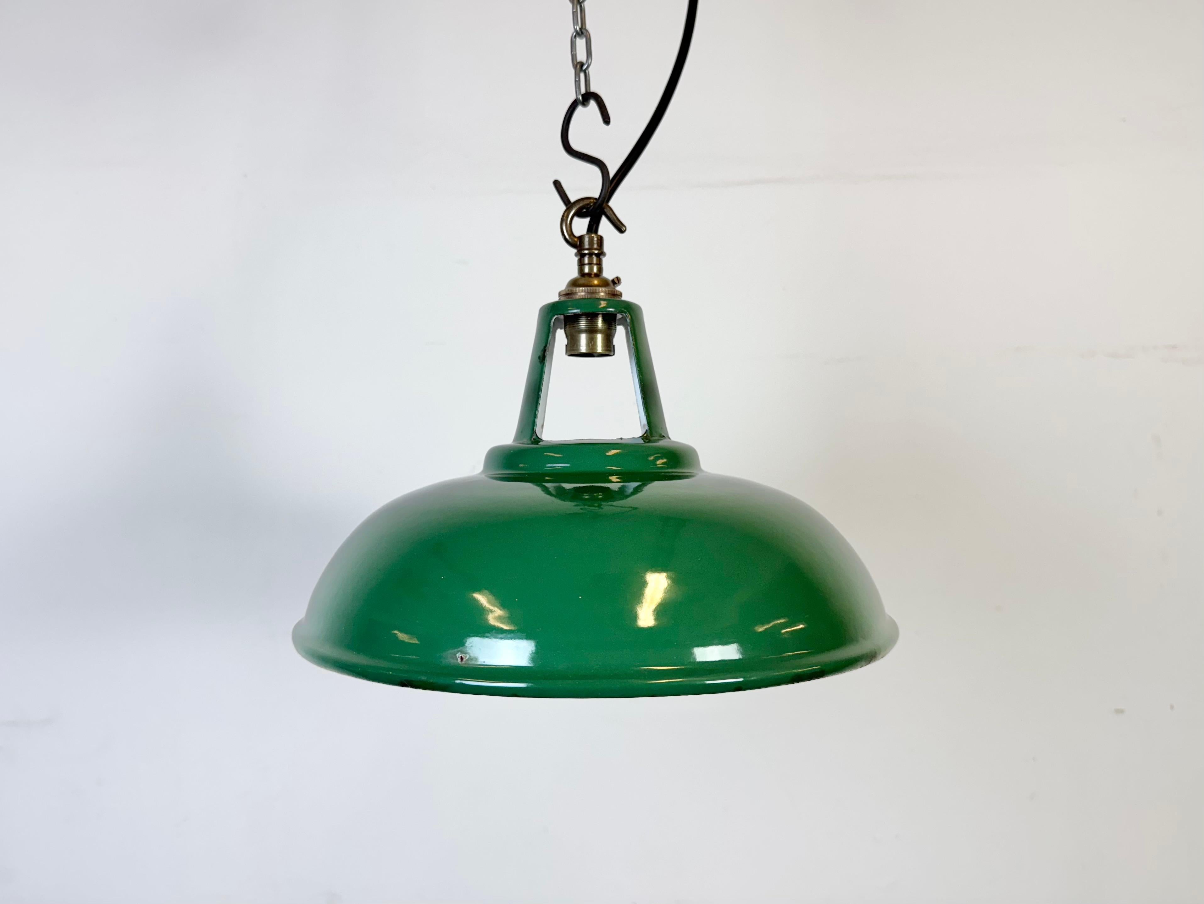 Industrial green enamel factory pendant light made in United Kingdom during the 1960s. White enamel inside the shade. Brass top. The socket requires B22 light bulbs. New wire. The weight of the lamp is 0,6 kg.The diameter of the shade is 27 cm.