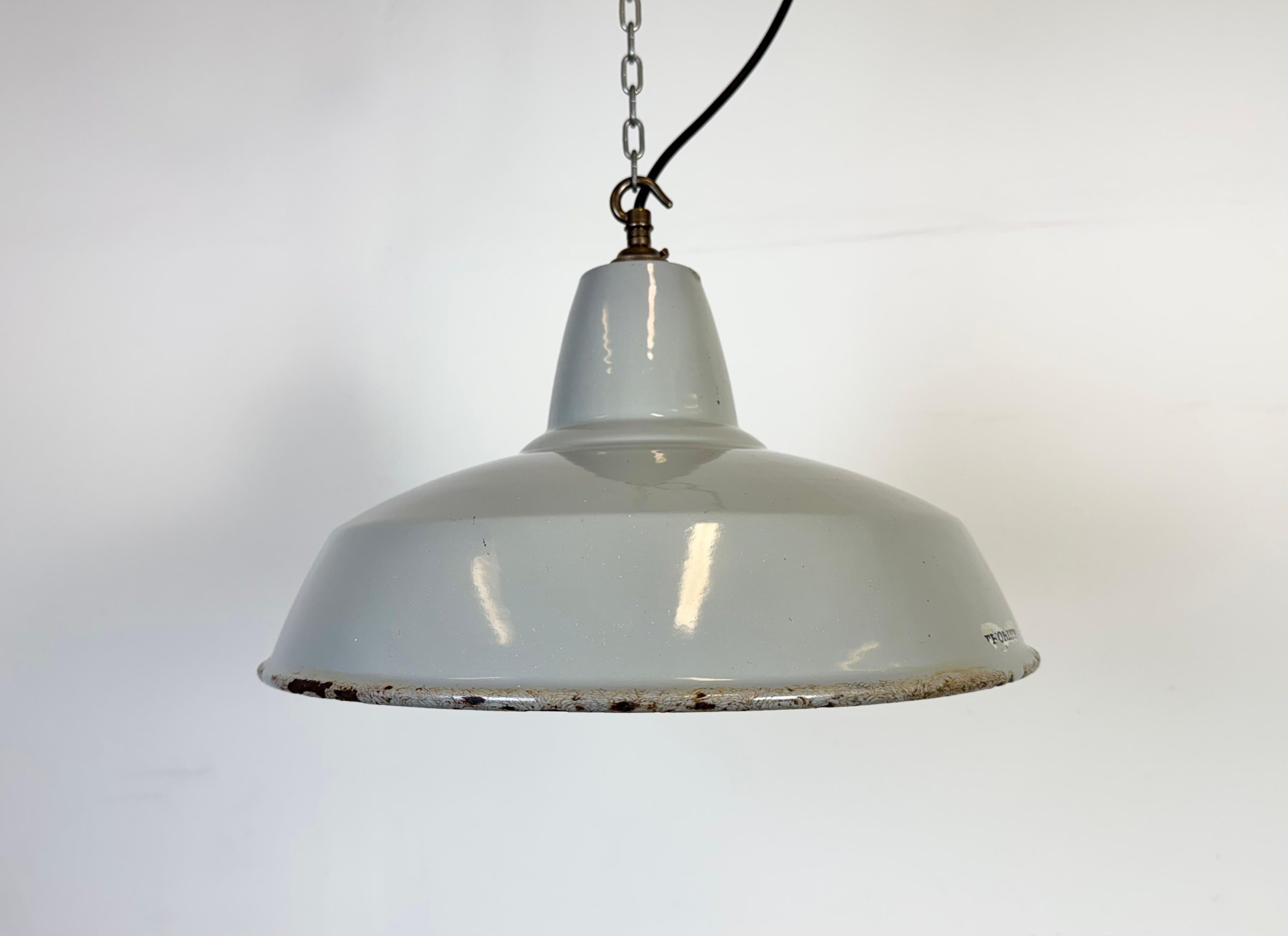 Suspension industrielle en émail gris fabriquée par Thorlux au Royaume-Uni dans les années 1960. Émail blanc à l'intérieur de la teinte. Dessus en laiton. La douille est compatible avec les ampoules B22. Un nouveau fil. Le poids de la lampe est de