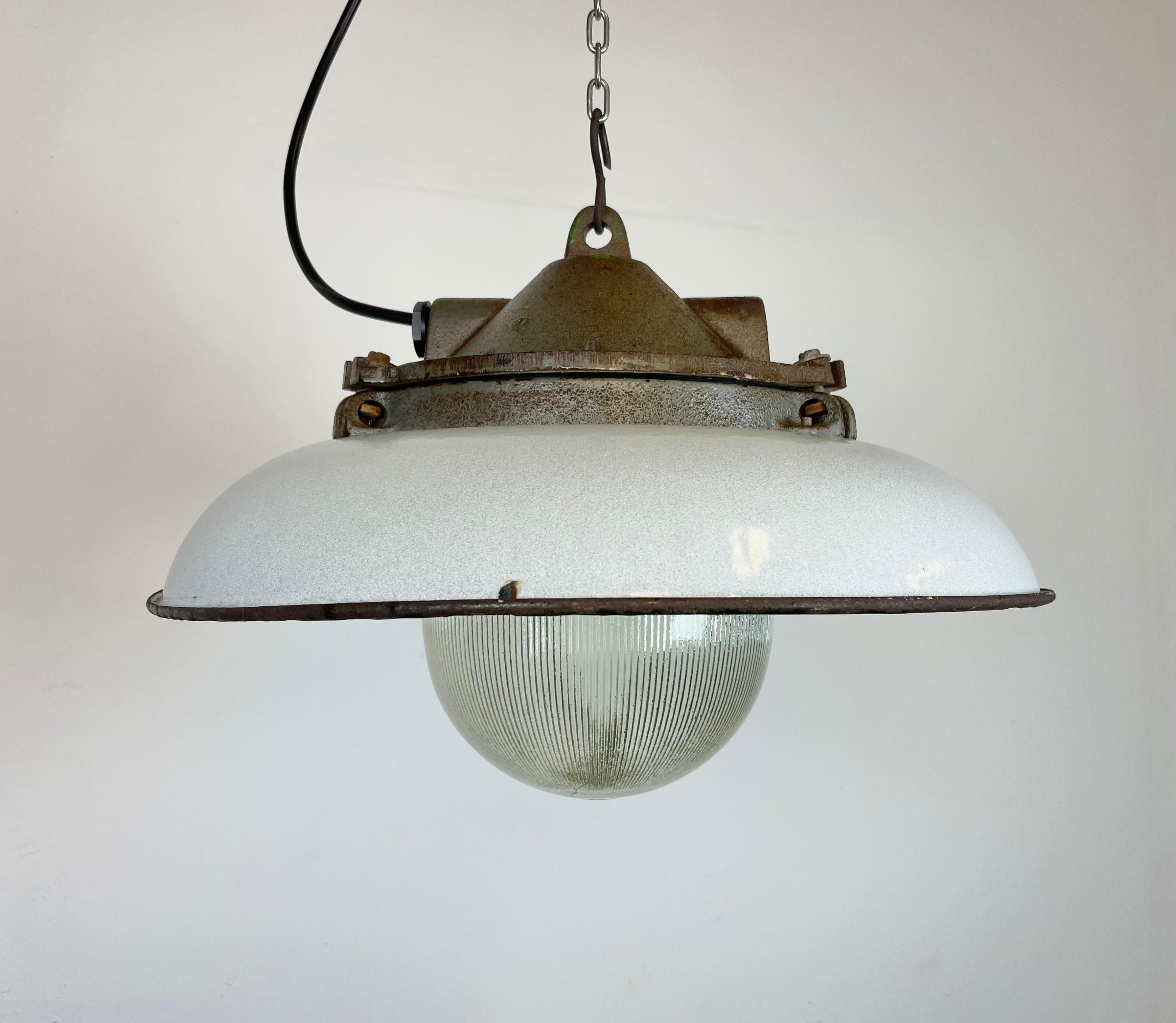 - Industrial factory pendant lamp in cast iron
- Manufactured by Zaos in Poland during the 1960s
- Light grey enamel shade with white enamel interior 
- Holophane glass cover
- Weight: 7 kg.