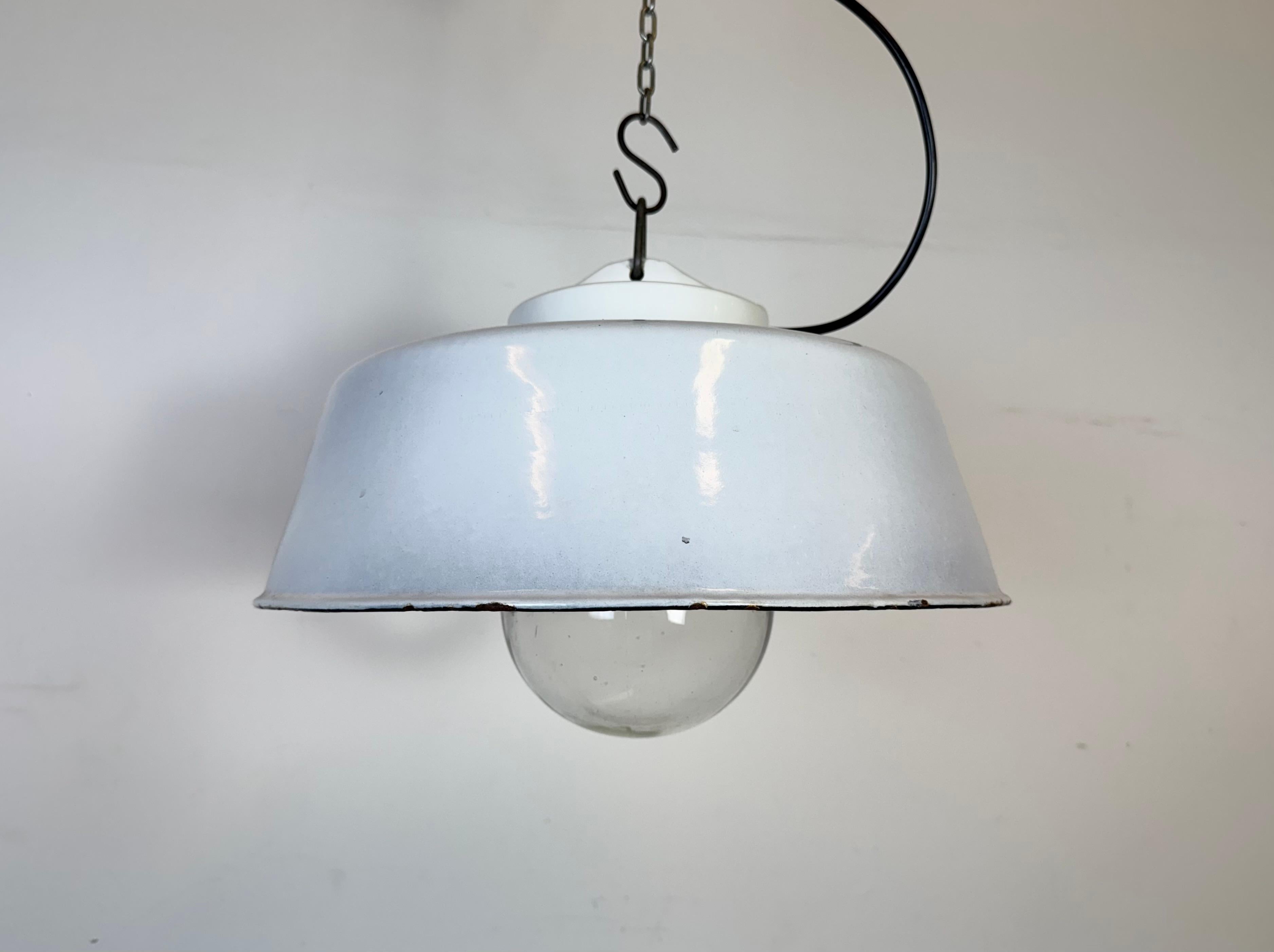 Lampada a sospensione industriale in smalto grigio chiaro realizzata nell'ex Cecoslovacchia negli anni '60. Smalto bianco all'interno del paralume. Piano in porcellana. Coperchio in vetro trasparente. L'attacco originale richiede lampadine standard