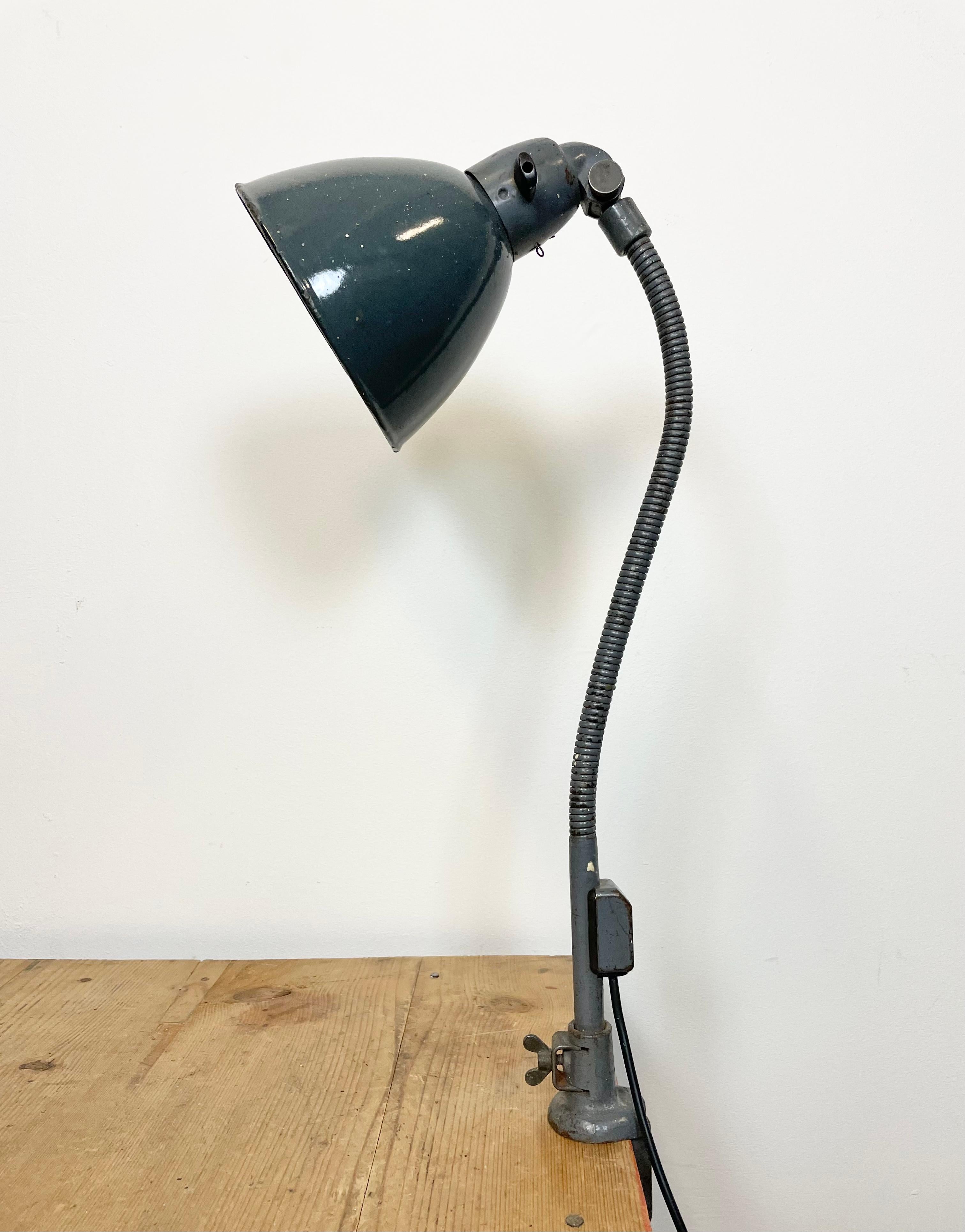 Industrial adjustable table lamp made by Siemens in Germany during the 1950s.It features grey enamel shade with white enamel interior, a cast iron clamp base and iron gooseneck. The original socket with switch requires E 27/ E 26 light bulbs.New