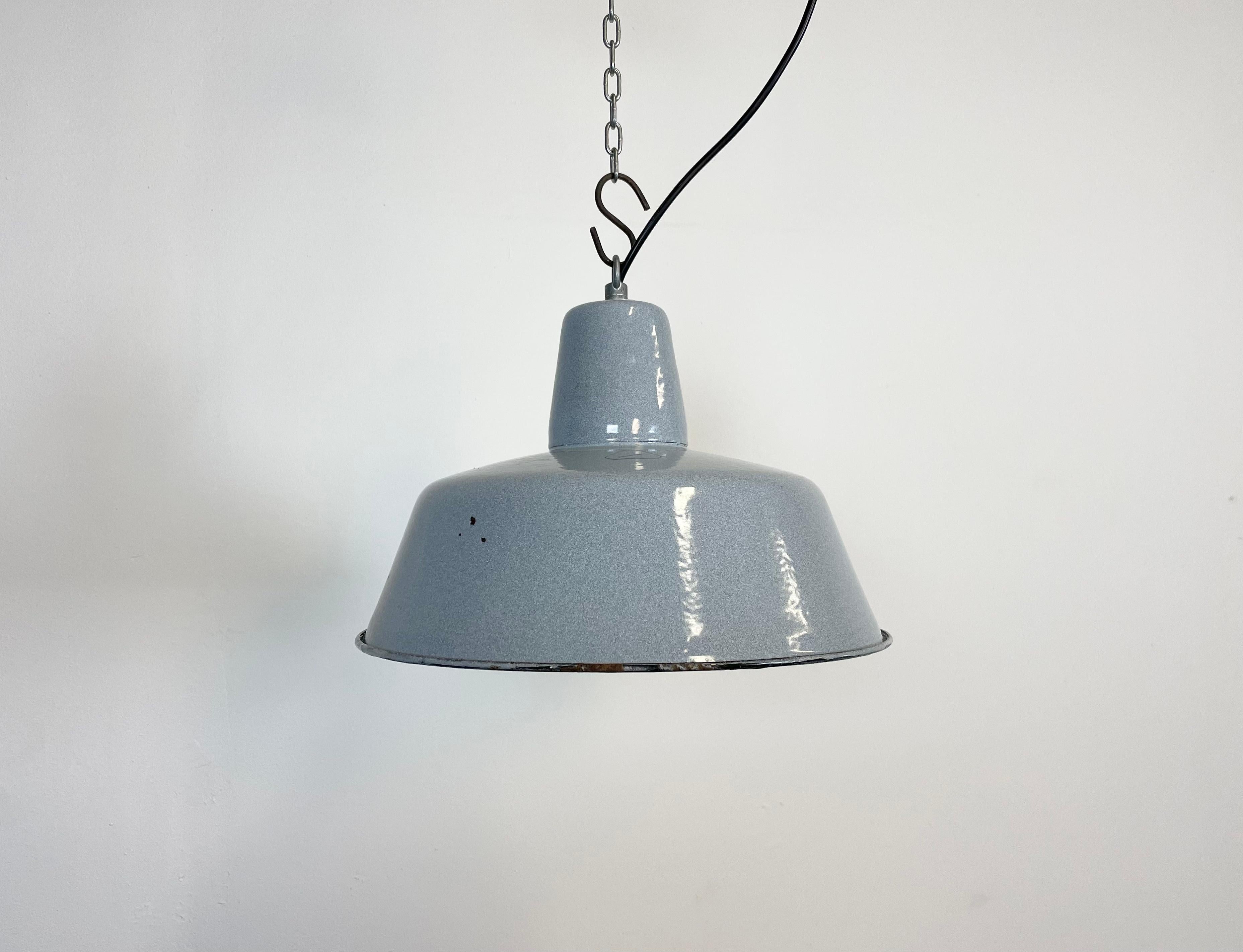Industrial blue grey enamel pendant light made by KWE in Poland during the 1960s. White enamel inside the shade. Iron top. The porcelain socket requires E 27 light bulbs. New wire. Fully functional. The weight of the lamp is 1,2 kg.