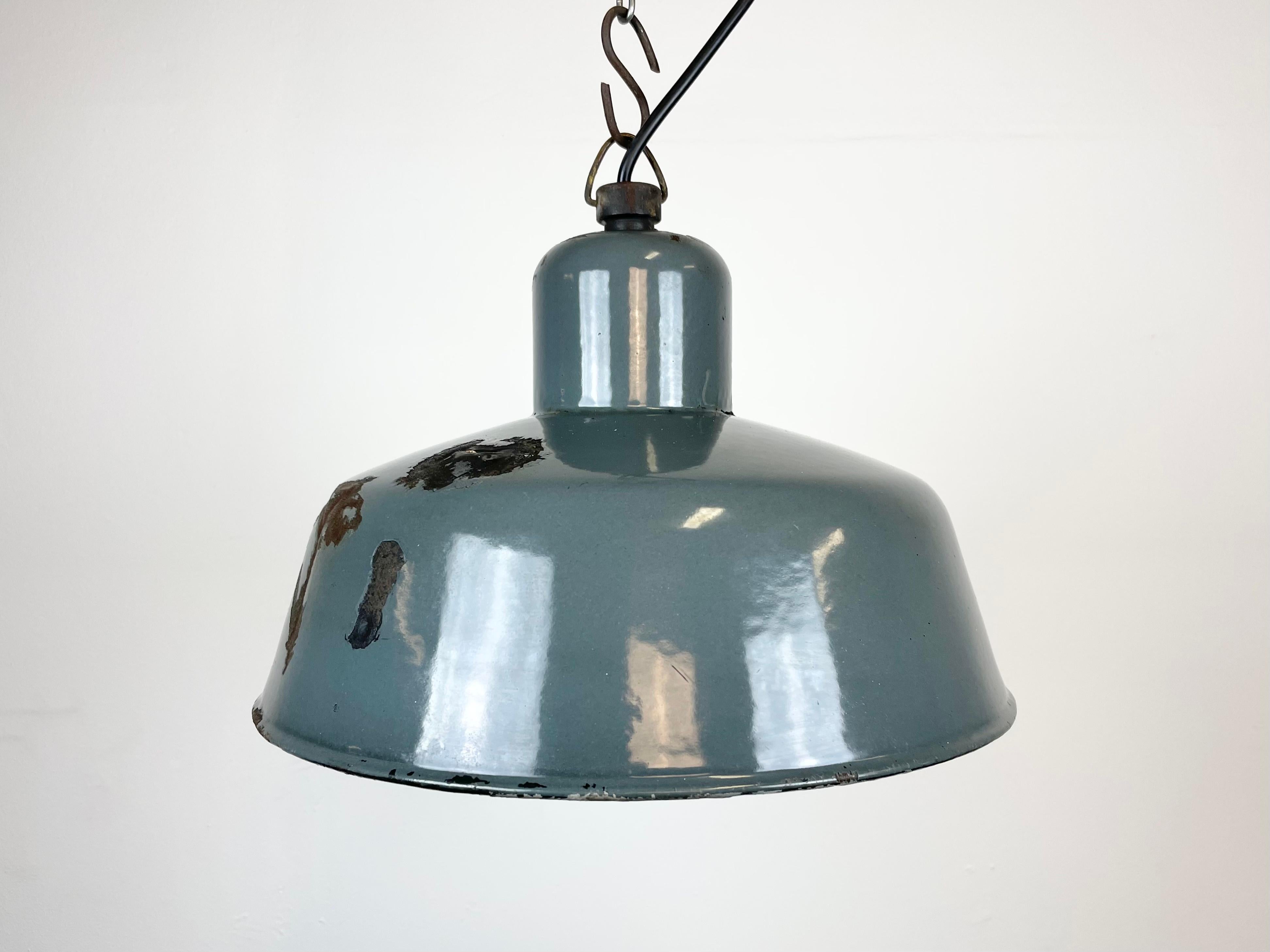Industrial grey enamel pendant light made by Siemens in Germany during the 1950s. White enamel inside the shade. Iron top. The porcelain socket requires E 27 light bulbs. New wire. Fully functional. The weight of the lamp is 1 kg. Unfortunately, the