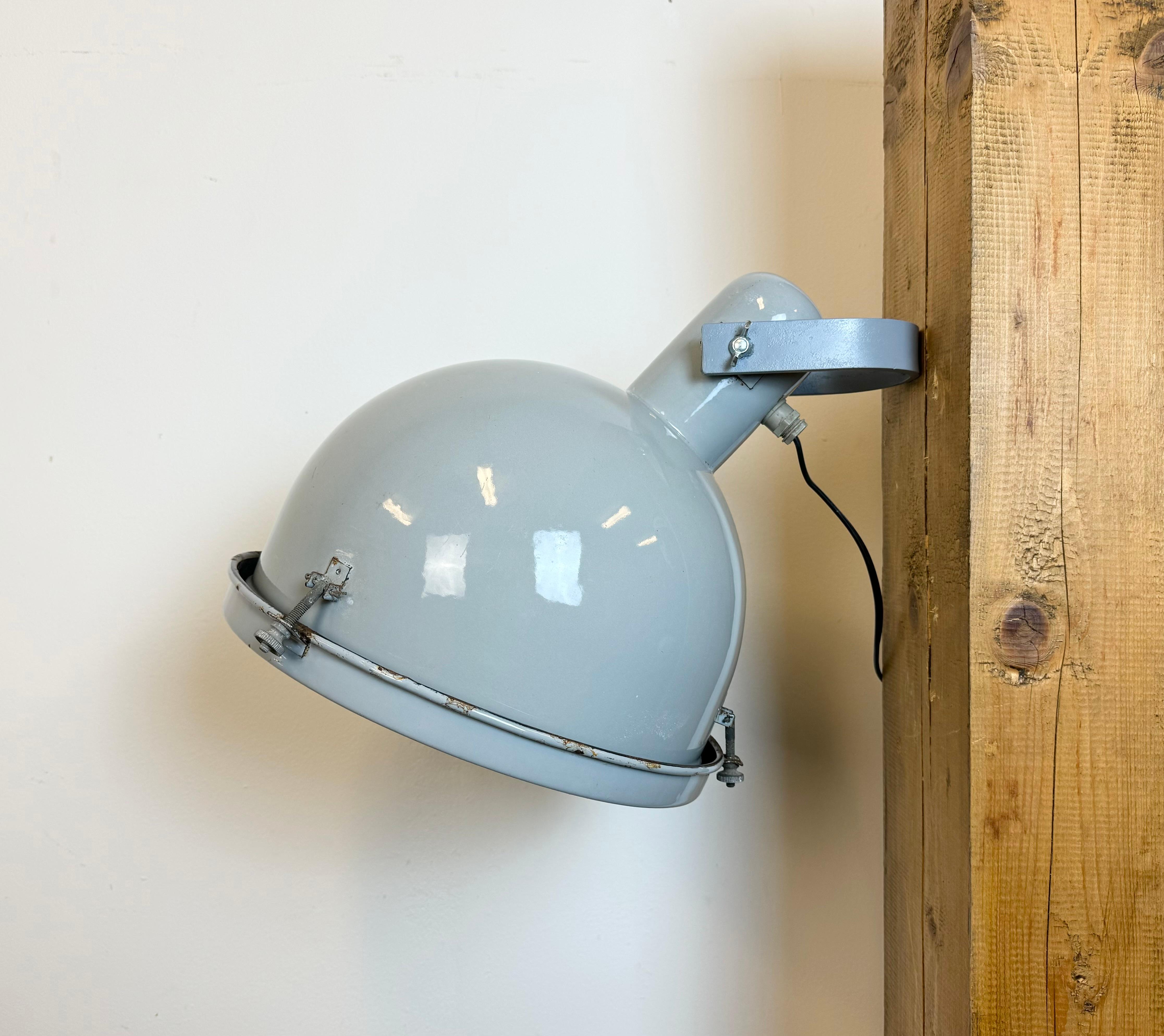 Industrial wall light with adjustable angle made in Italy during the 1960s. It features a  grey  enamel shade with white enamel interior, an iron wall mounting and a clear glass cover. The porcelain socket requires E27/E26 light bulbs. New