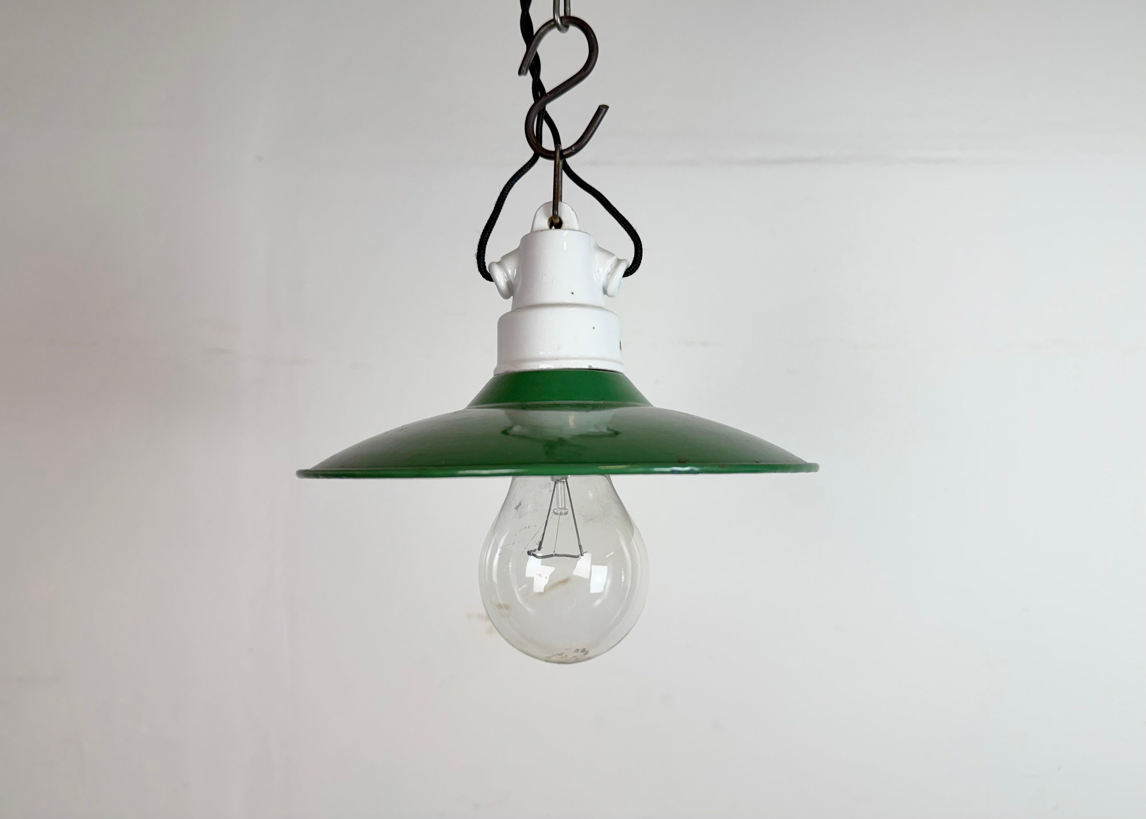 Vintage industrial enamel pendant lamp made in former Czechoslovakia during the 1950s. It features a green enamel shade with white enamel interior and porcelain top. The socket requires standard E 27/ E 26 light bulbs. The lampshade diameter is 20