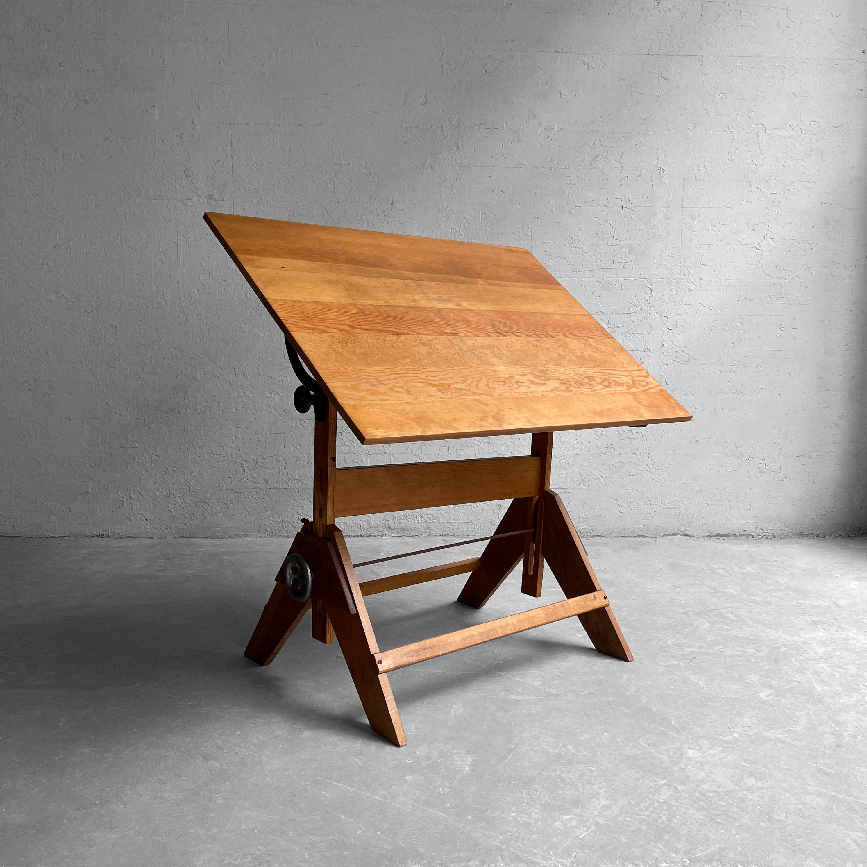 Early 20th century, industrial, drafting table features a maple base with pine top and cast iron hardware. The table's height is adjustable from 31-40 inches. The top rotates vertical on both sides and can be set at level horizontal.